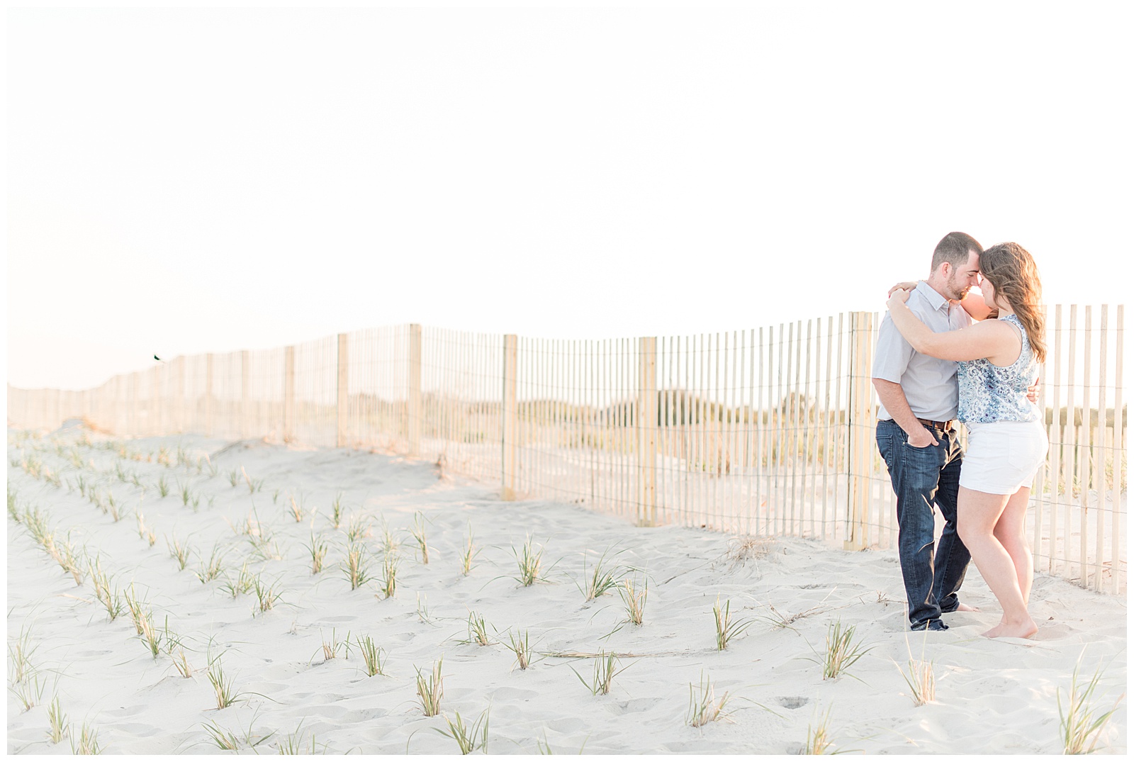 couple standing along fence on beach