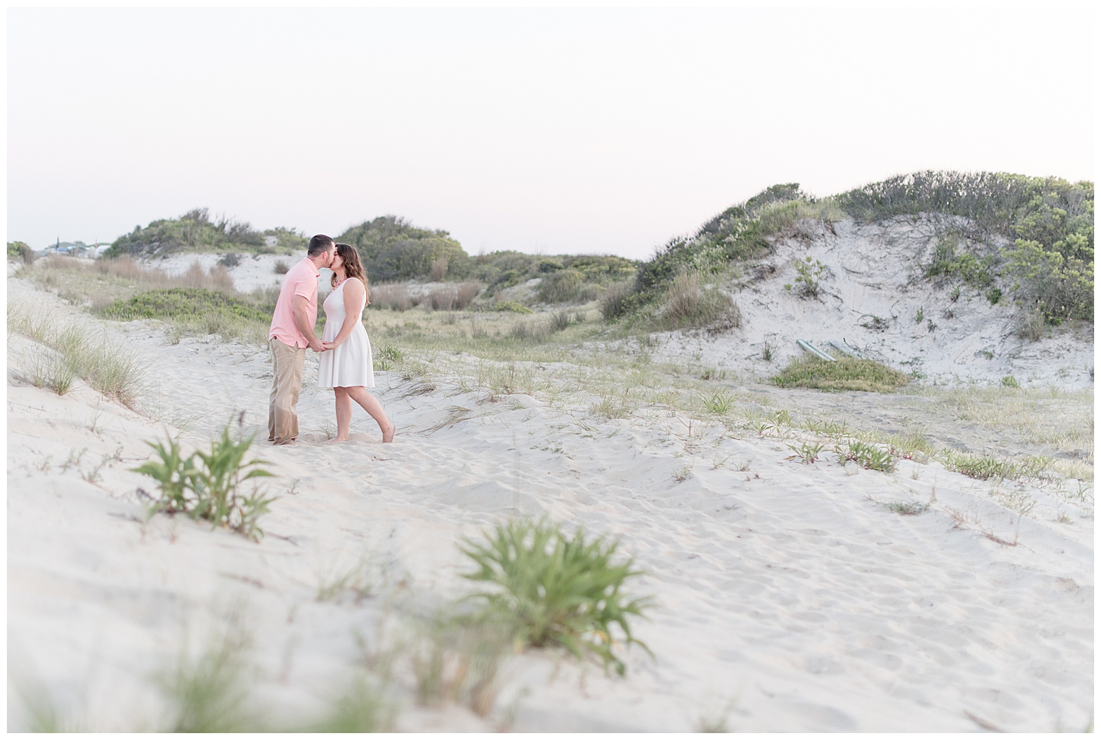 couple kissing beside beach dunes