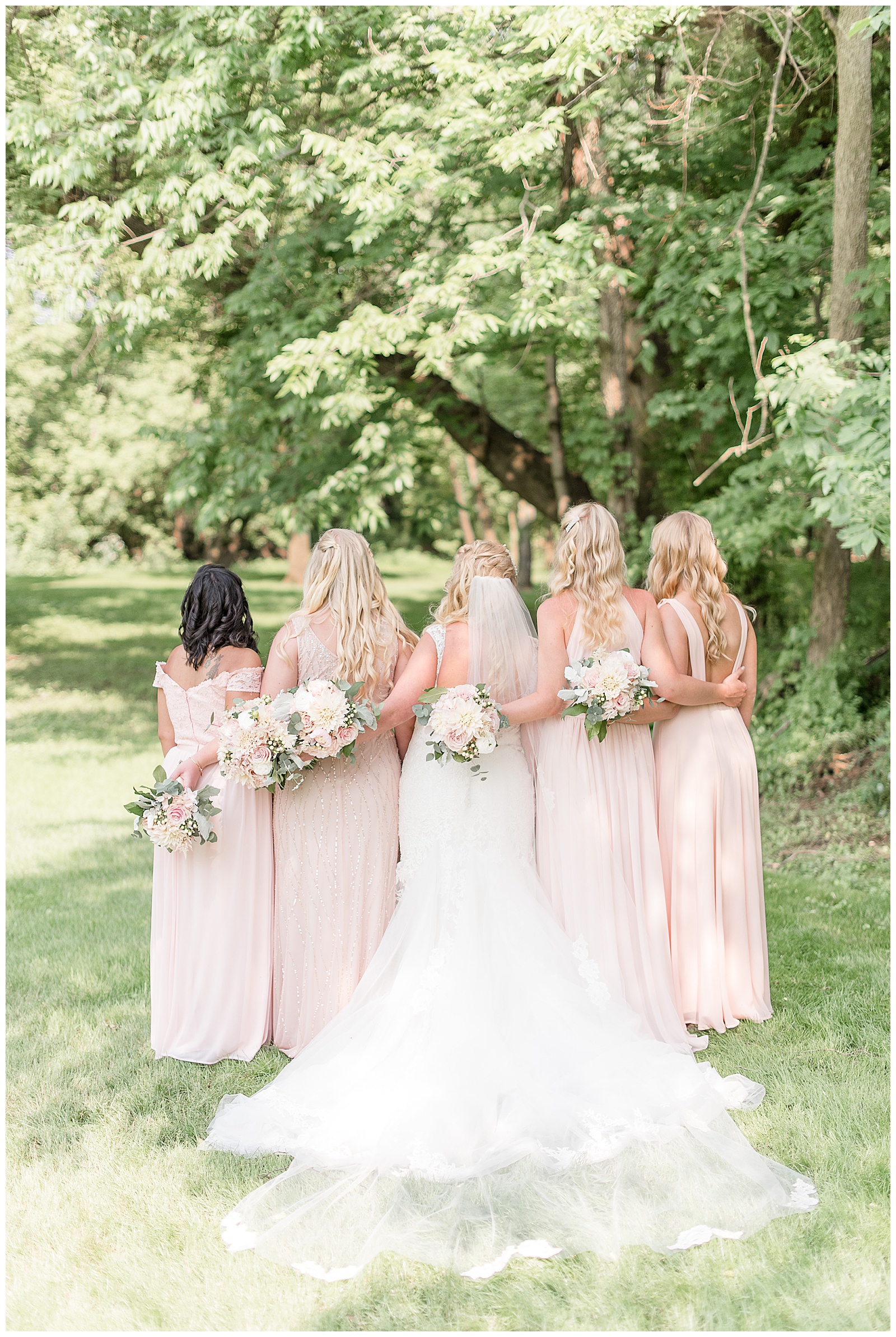 bridesmaids with backs to camera and arms around each other's backs