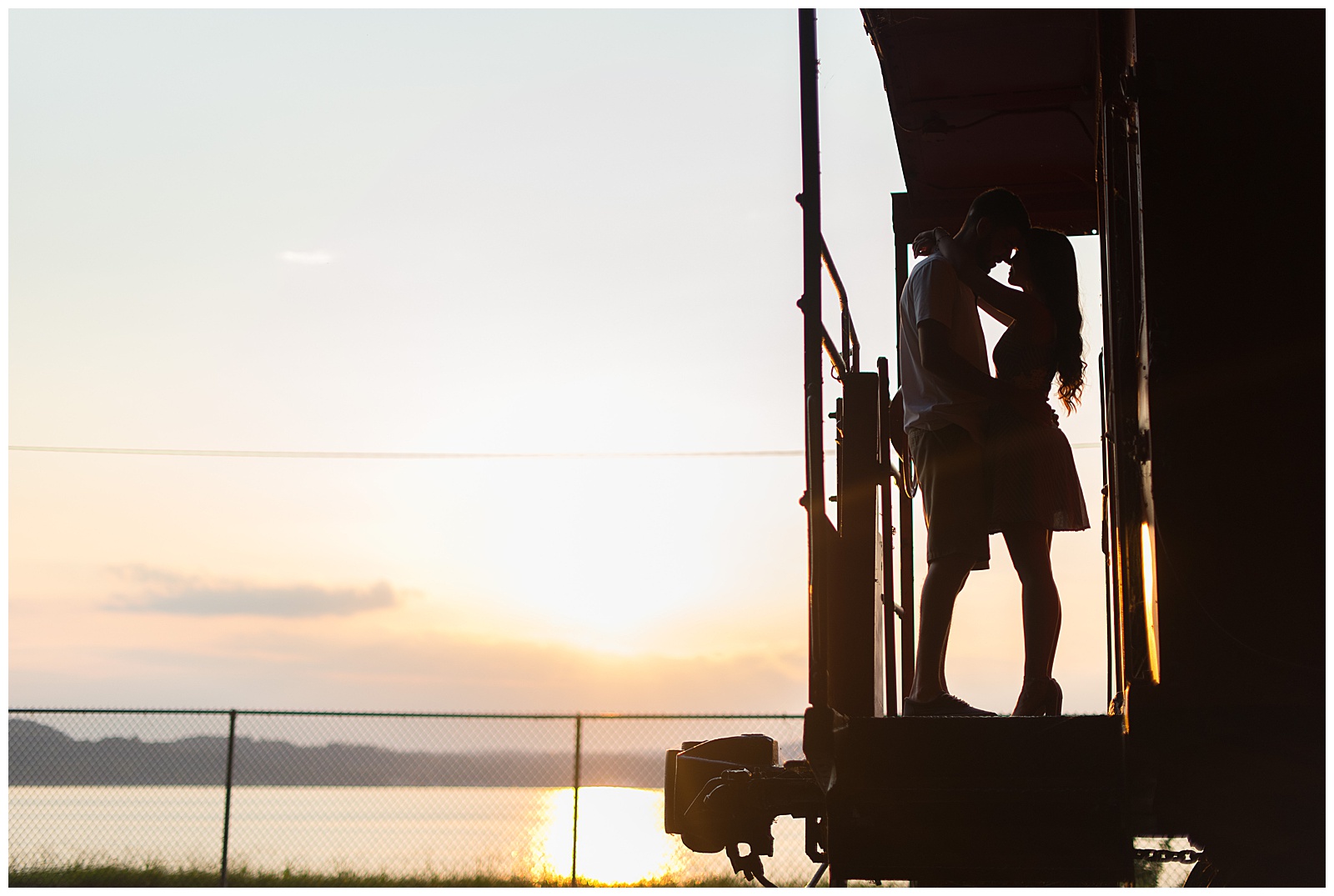 couple kissing on caboose with sunset behind