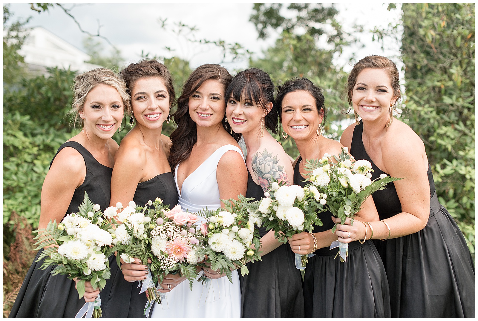 bridesmaids all hugging in close and smiling at camera