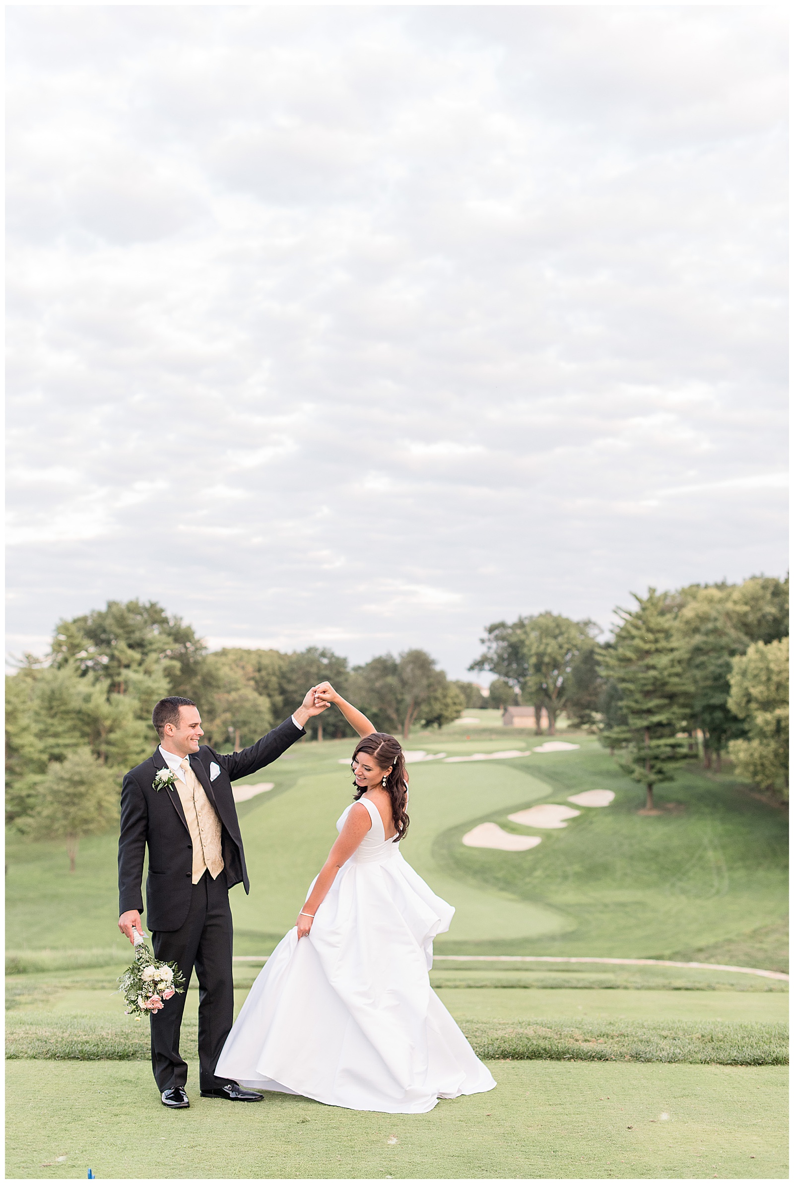 groom twirling bride on golf green overlooking golf course