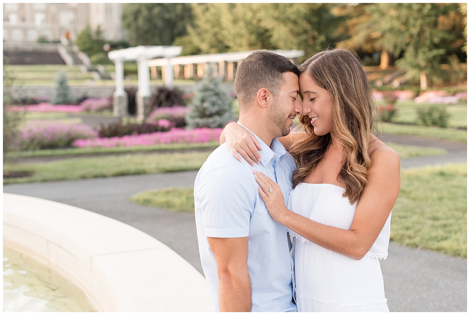 couple nuzzling in close with noses touching at side of fountain