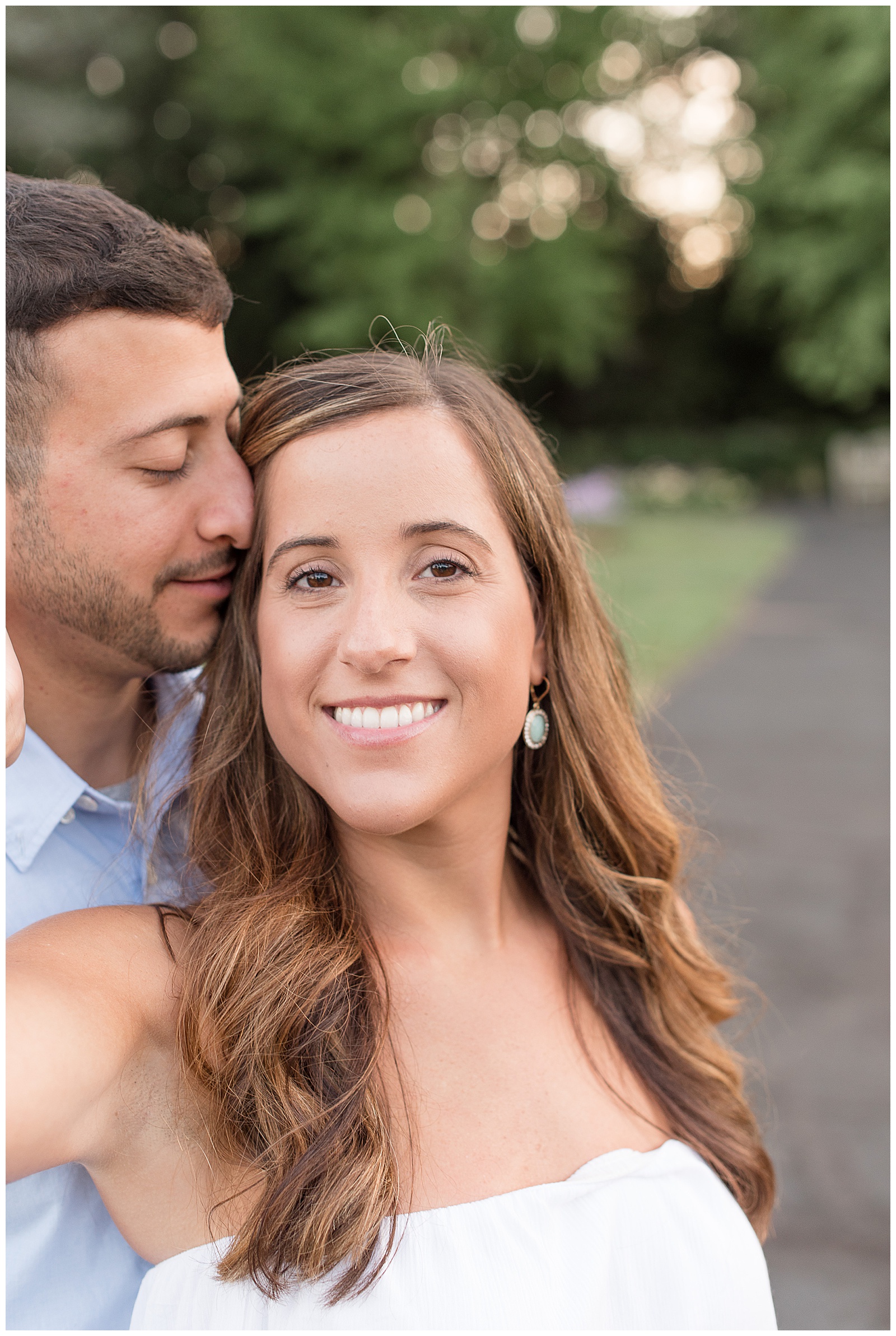 girl smiling at camera while guy nuzzles in