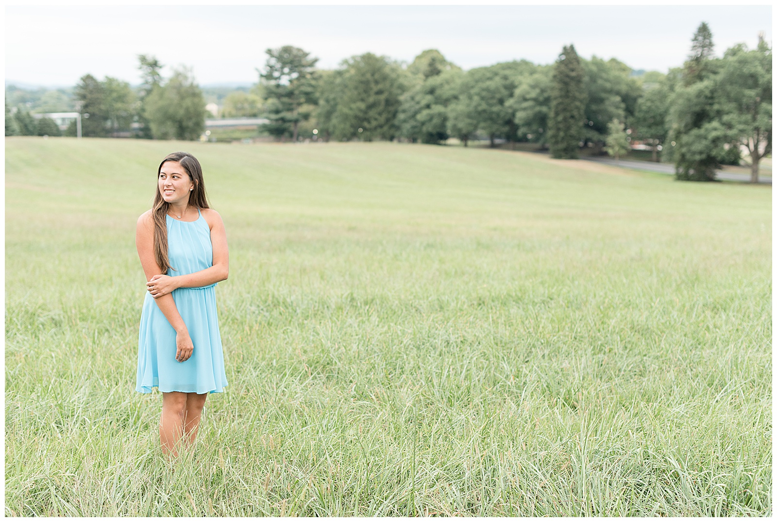 senior girl in a field of tall grass looking off to left