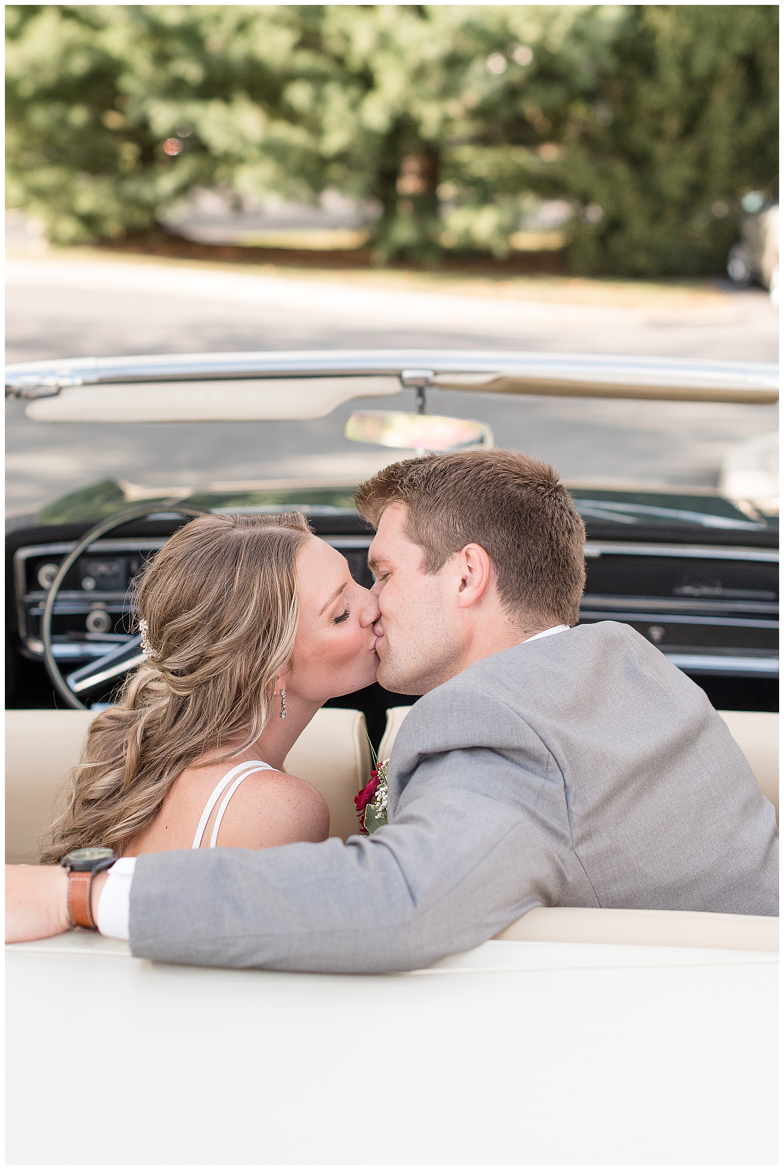bride and groom kissing in back seat of old buick convertible