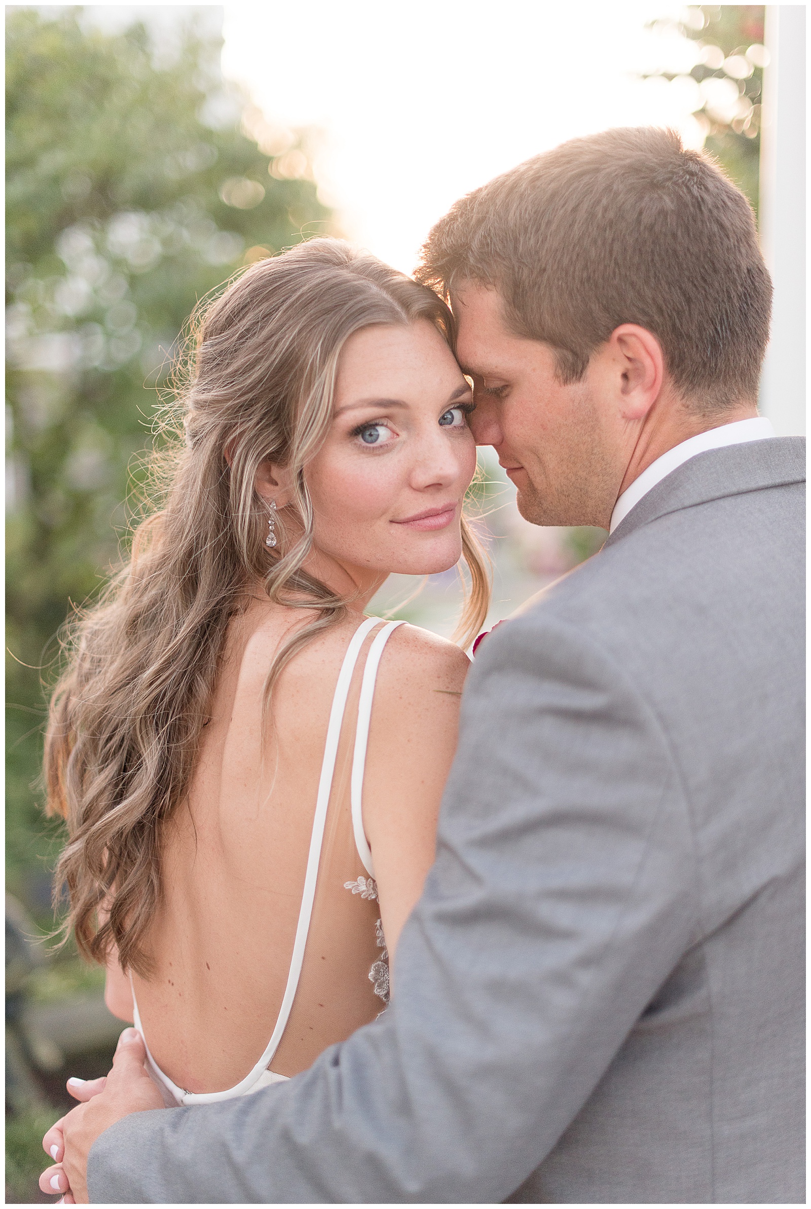 bride looking over shoulder at camera and groom nuzzling into her cheek