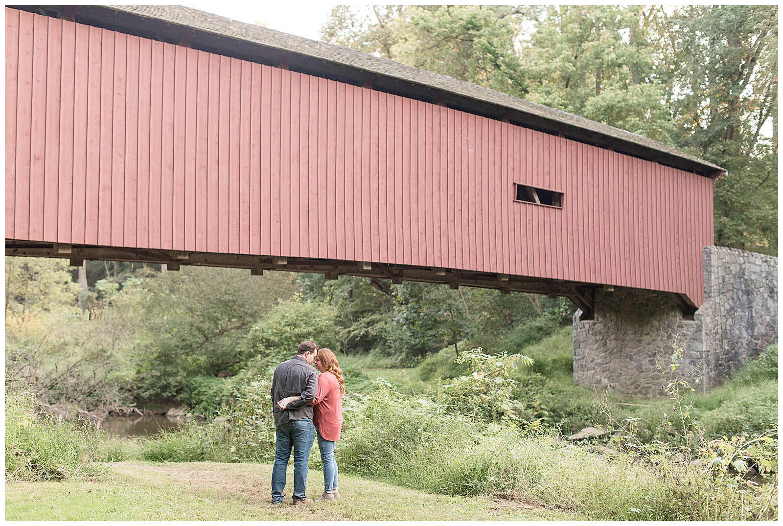 Engagement Session Photos at Lancaster County Park with couple going nose to nose in front of covered bridge
