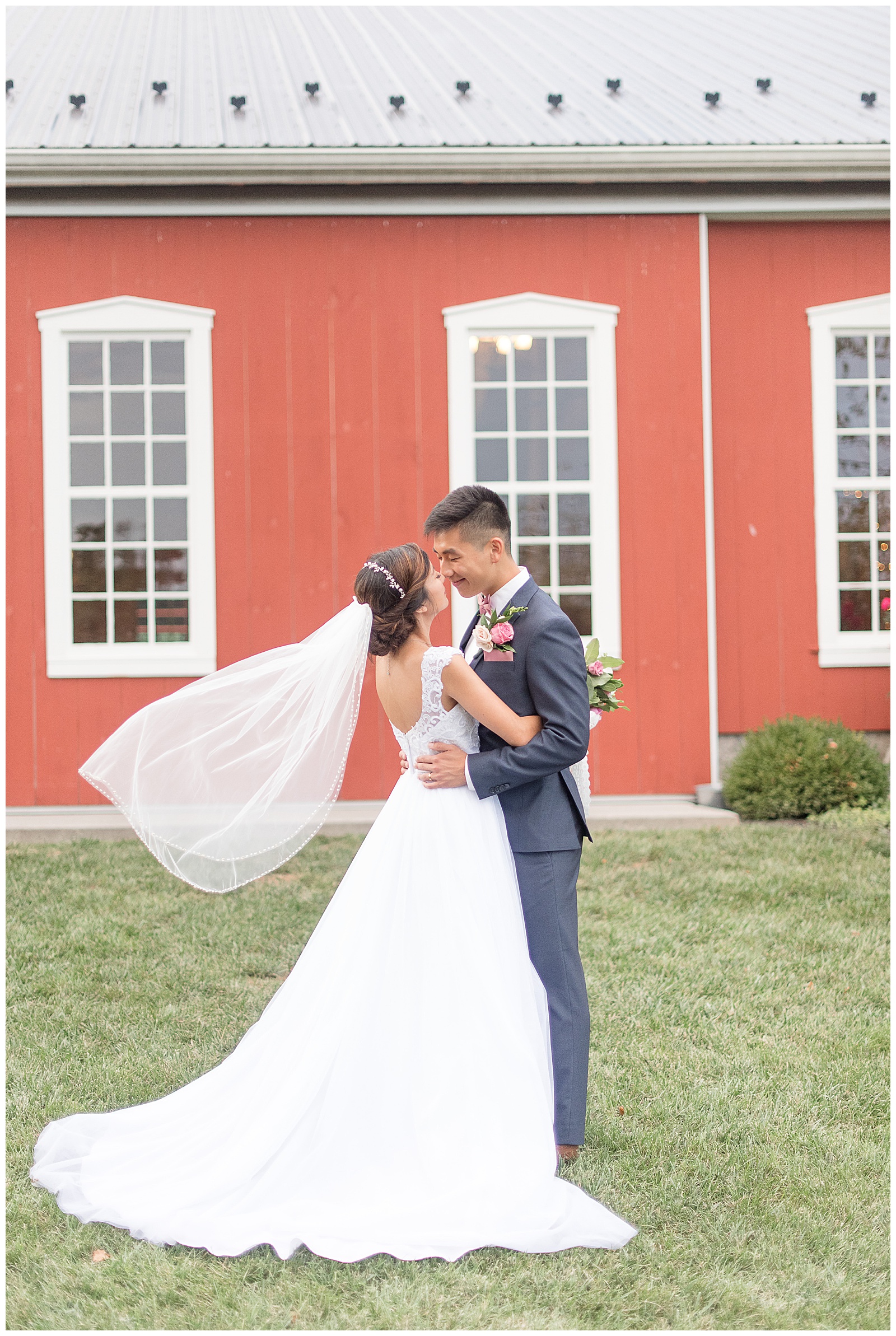 husband and wife portrait in front of barn at Pond View Farms