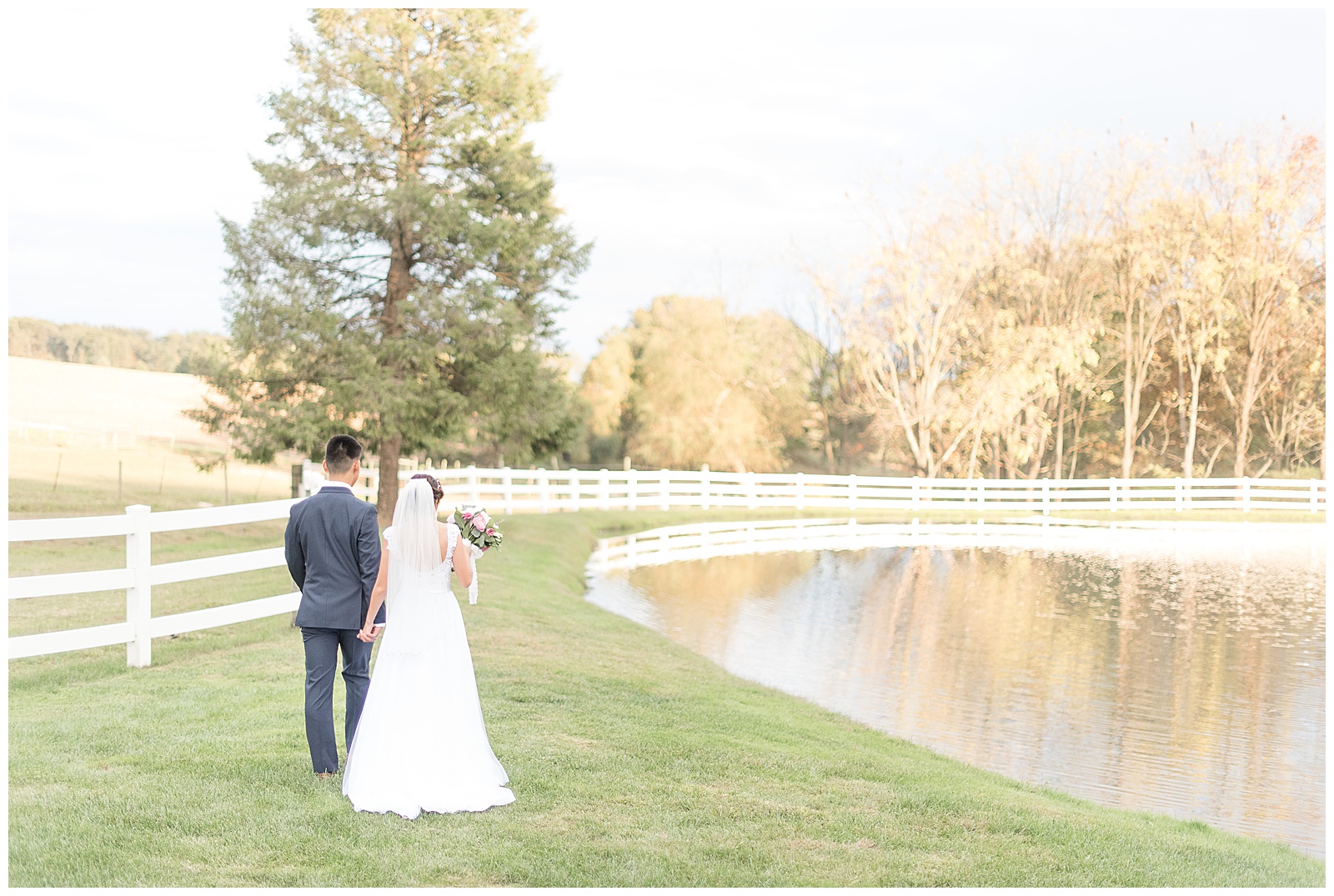 bride and groom walking along pond hand in hand