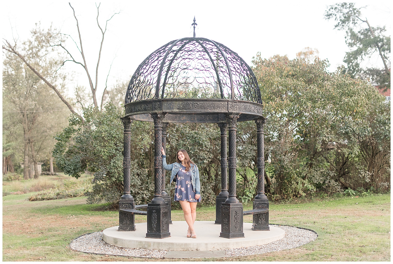 senior girl leaning against post of gazebo looking off to side