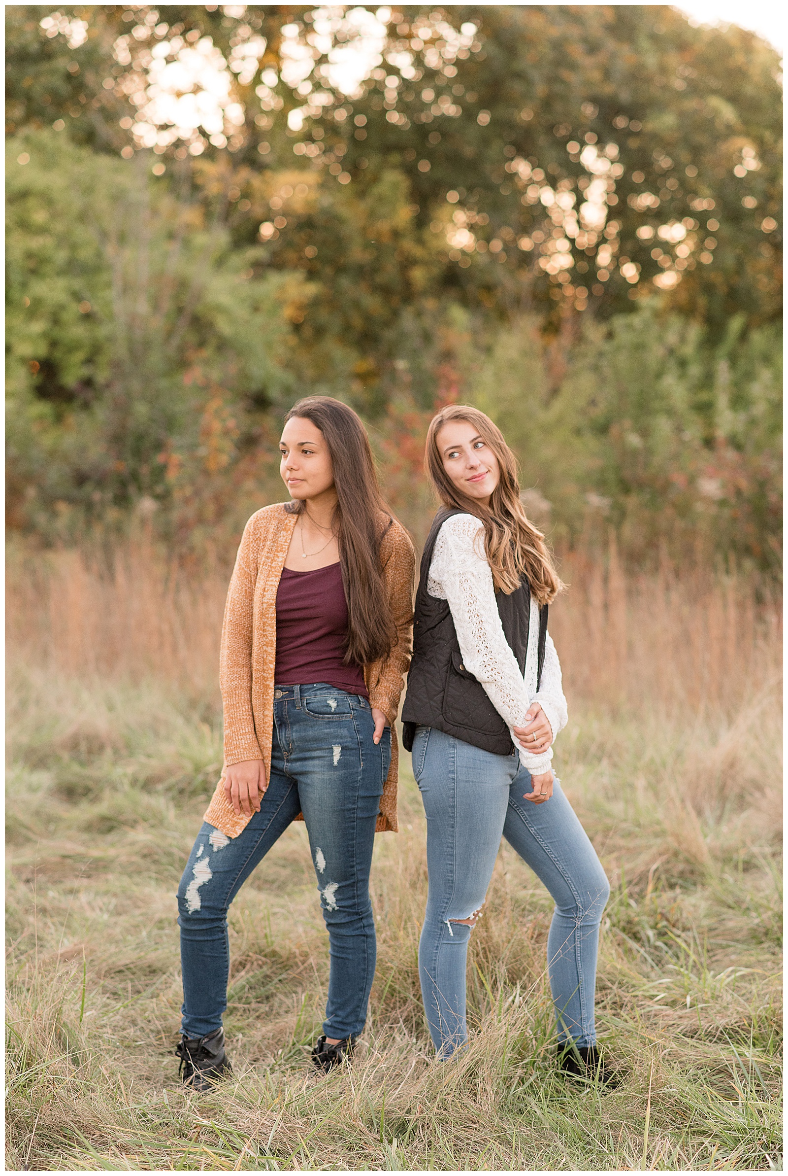 seniors standing in tall wild grass field looking over shoulders off camera