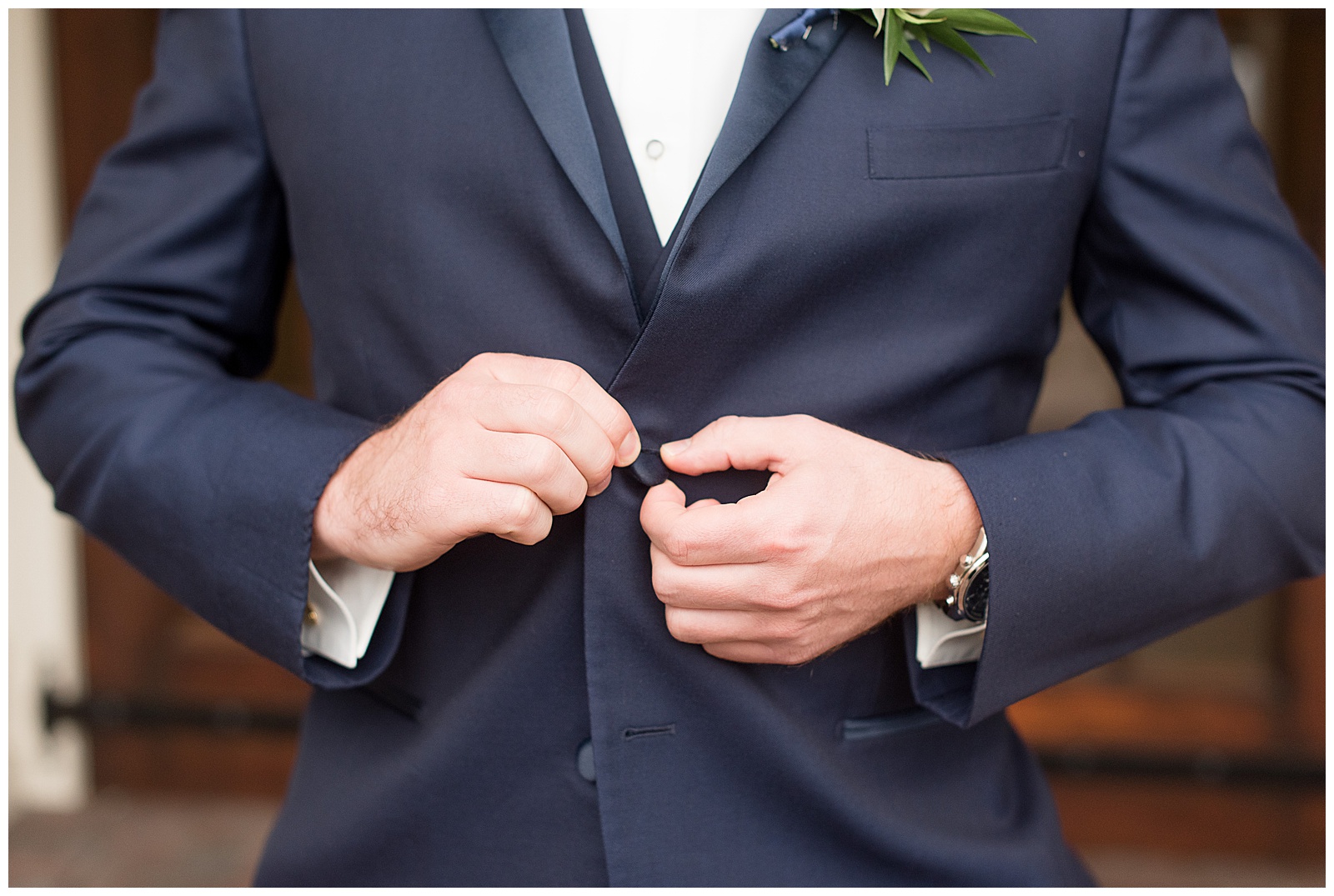 groom buttoning his jacket