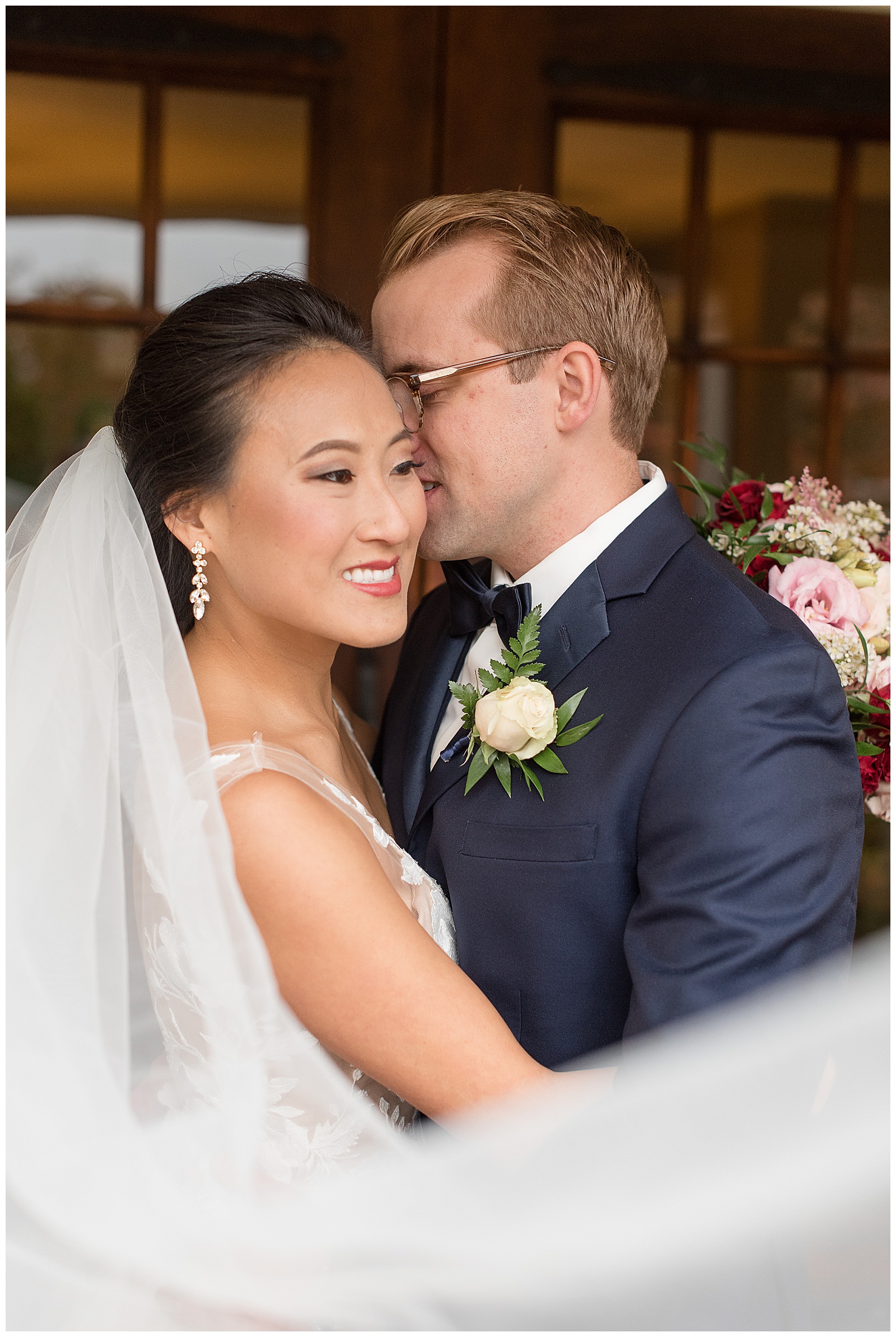veil shot with husband nuzzling into brides temple and she is smiling off camera