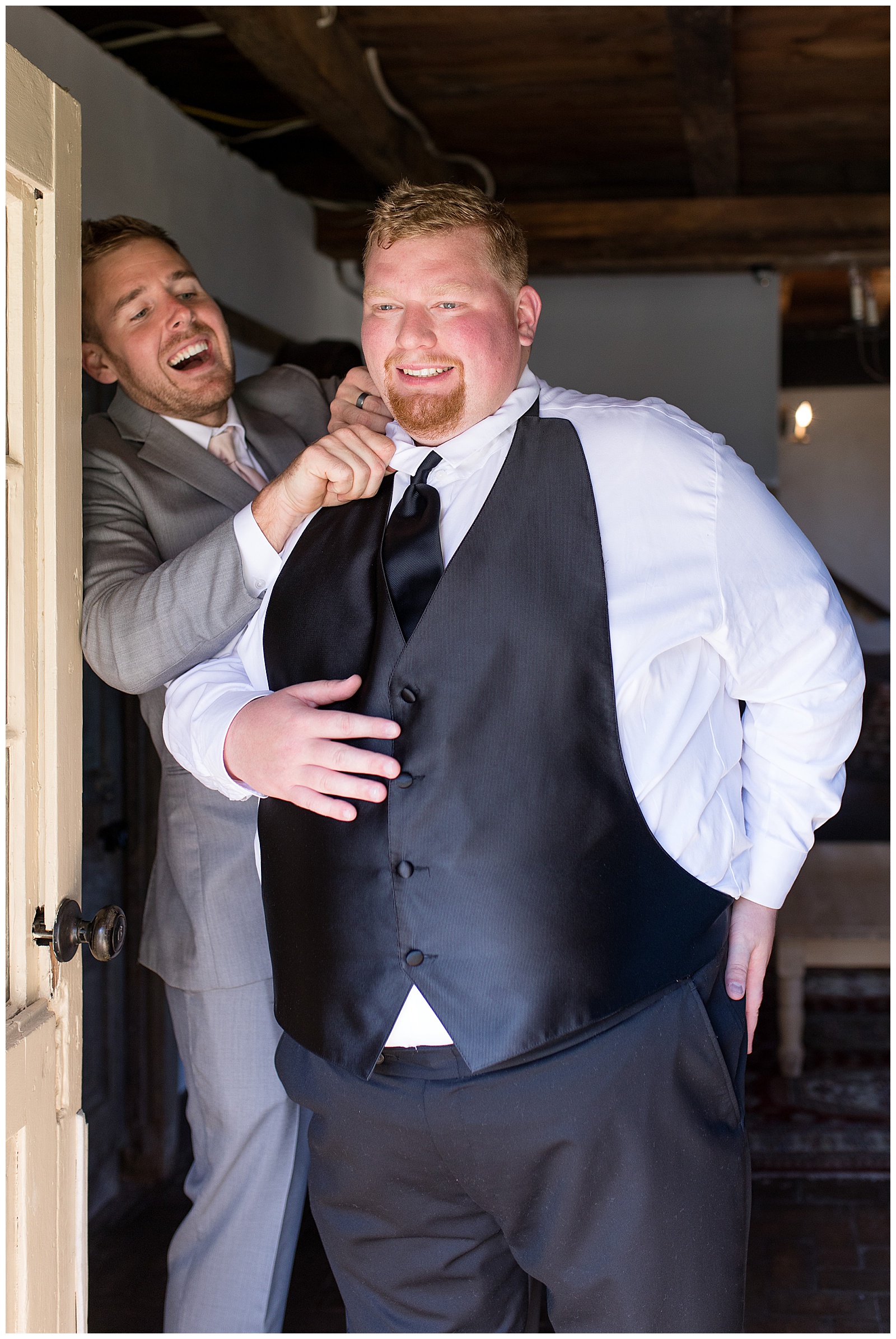 groom getting dressed with help from best man