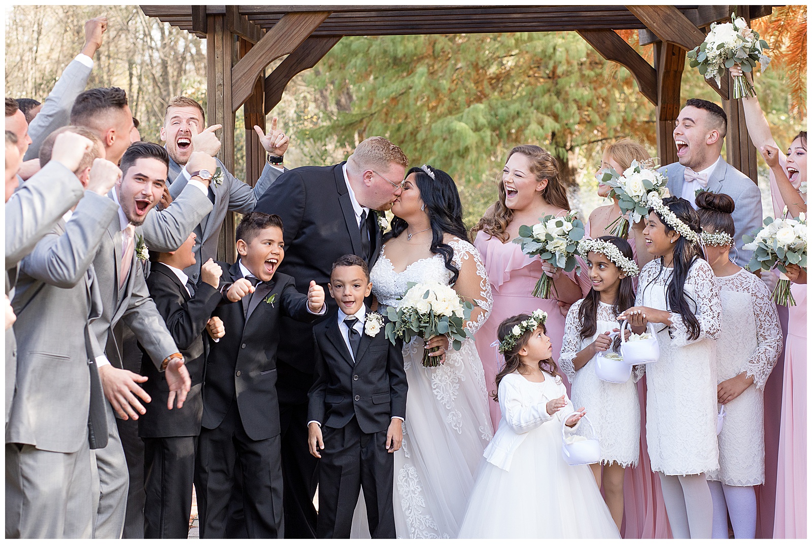 bridal party cheering as bride and groom share a kiss