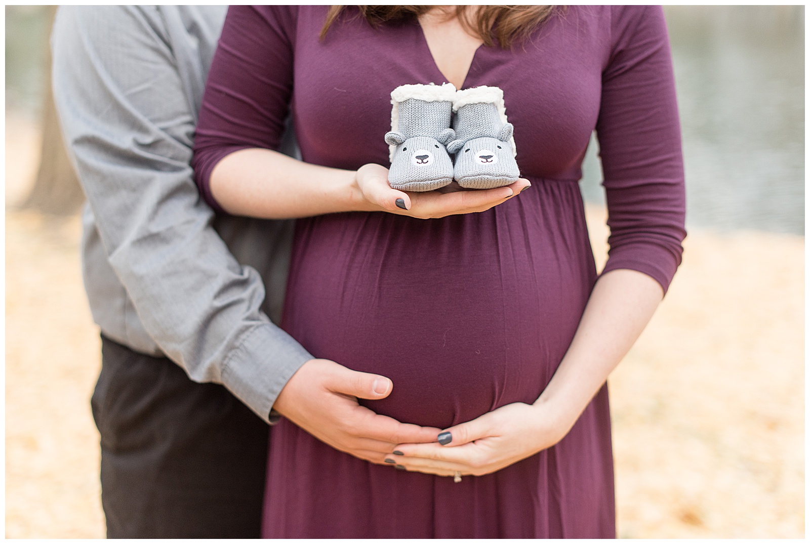 woman holding baby shoes and her and husband holding under belly