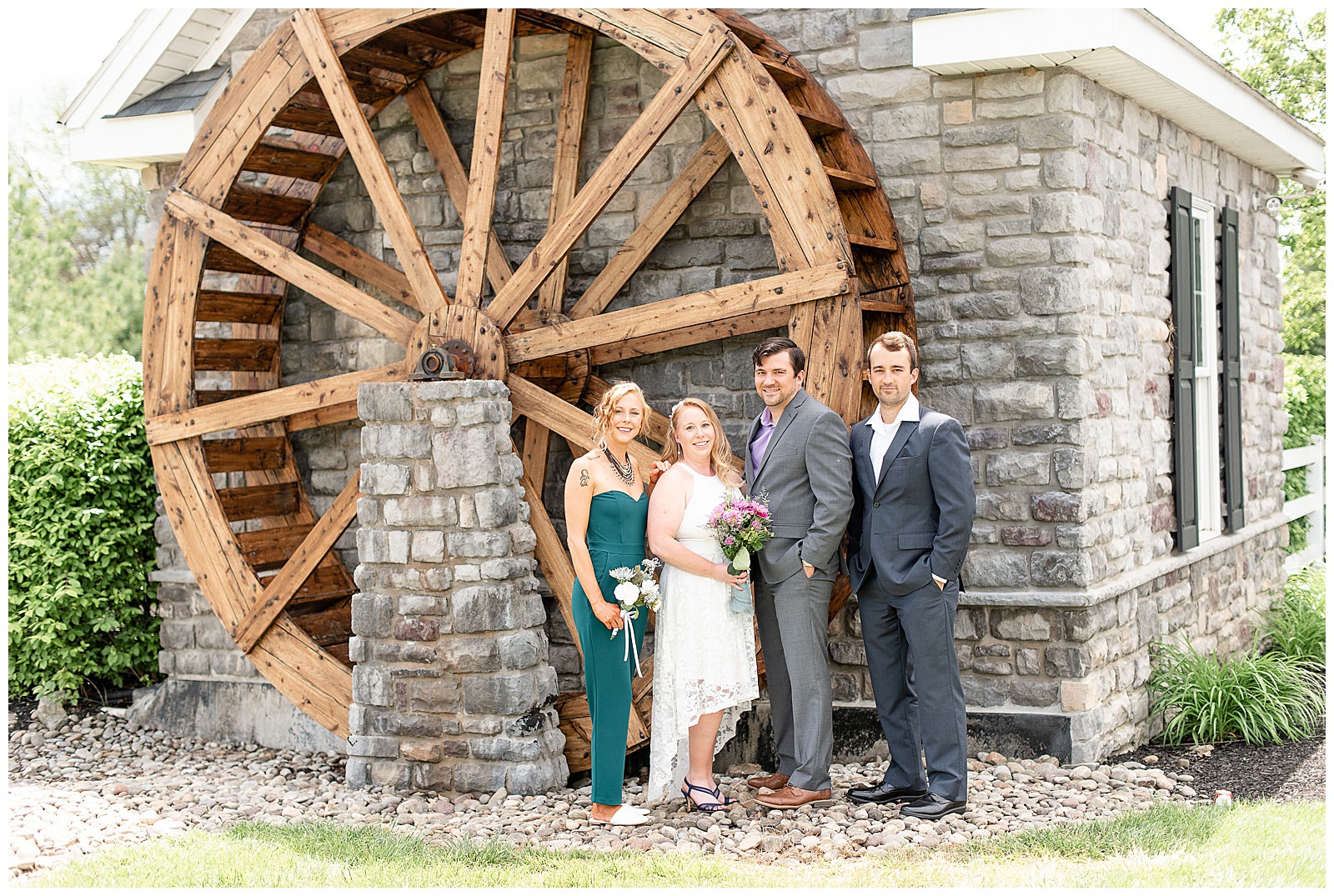 bridal party in front of wood water wheel