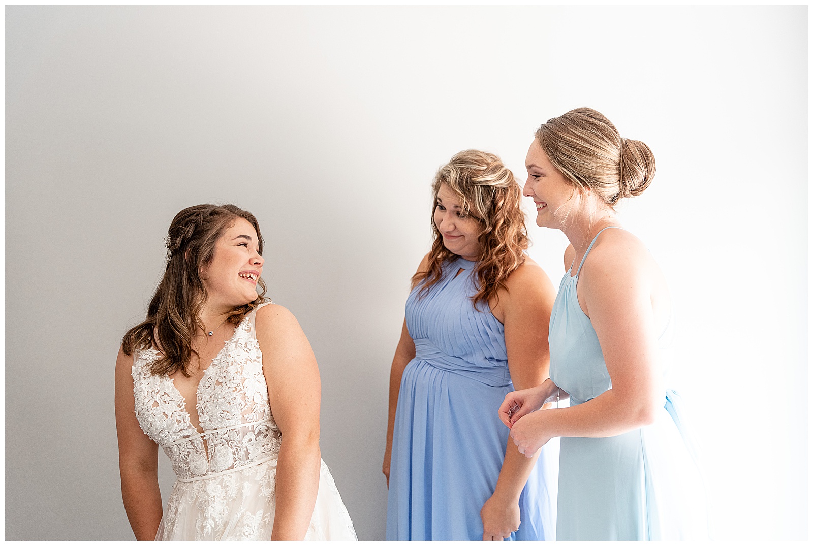 maid of honor and sister helping bride get zipped up in dress