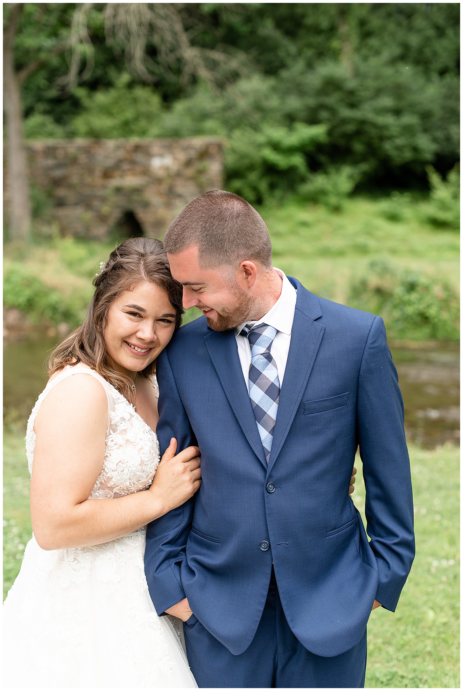 bride smiling at camera holding on to grooms arm as she smiles down to him