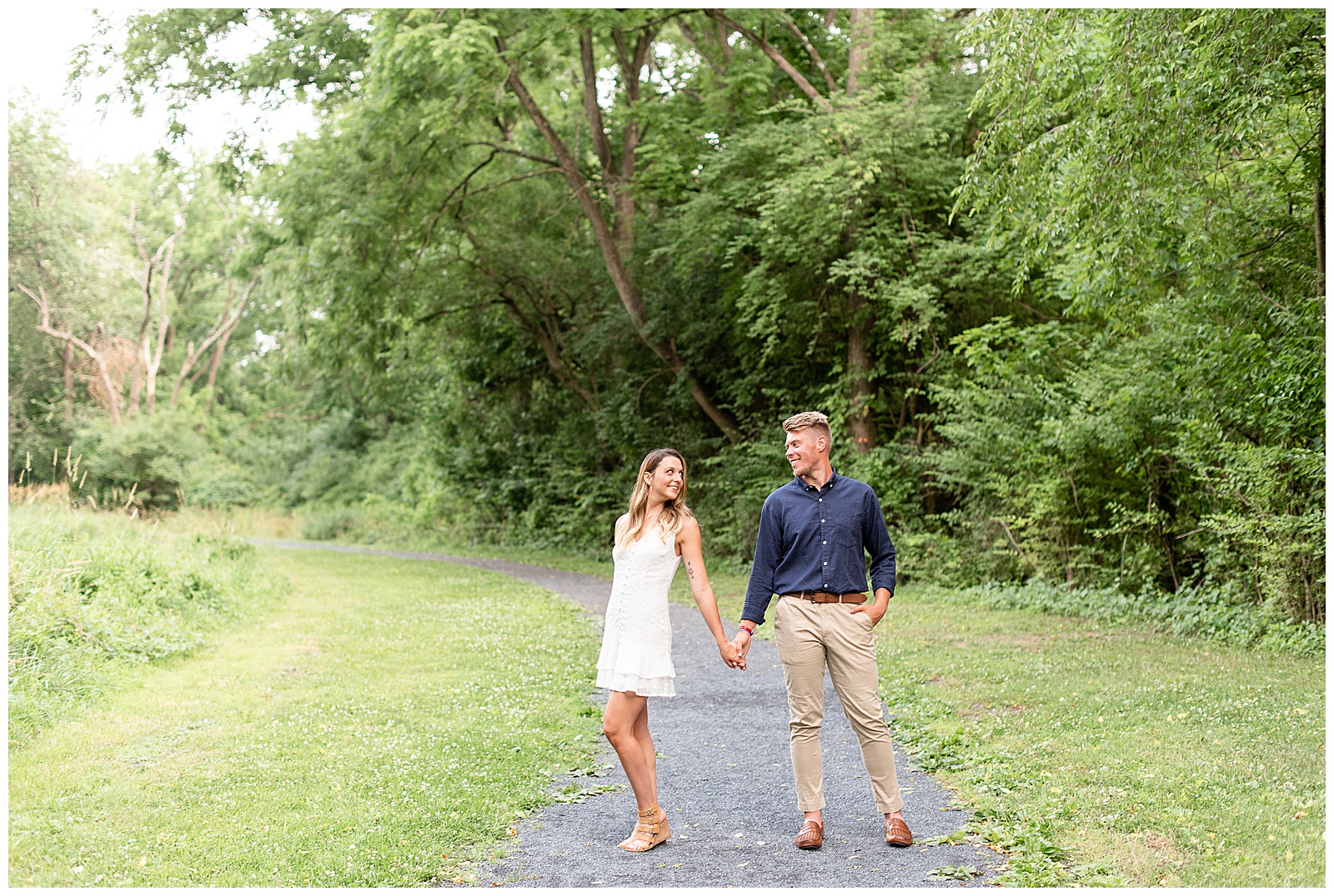 couple holding hands on stone path way and looking towards each other and smiling
