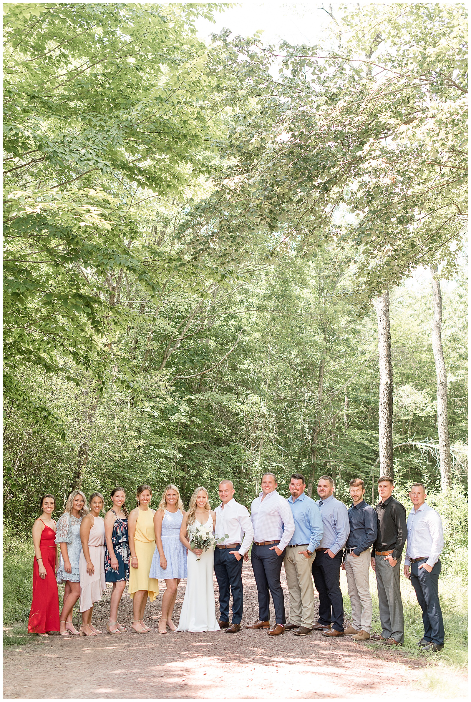 full bridal party smiling at camera with woods all around