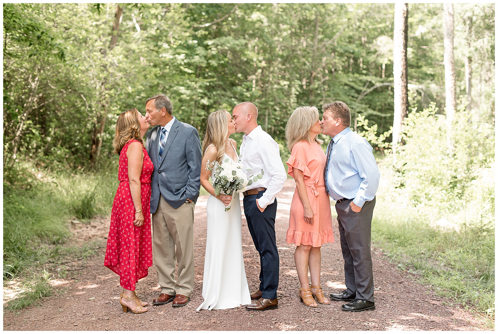 bride and groom with both sets of parents with each couple sharing a kiss