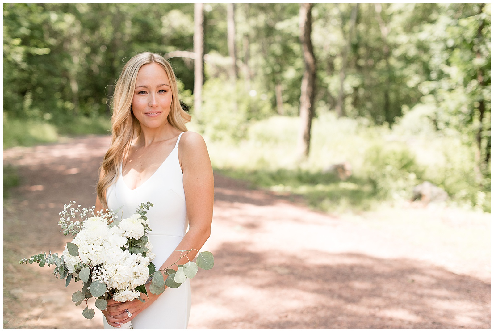 bride smiling at camera holding wedding bouquet