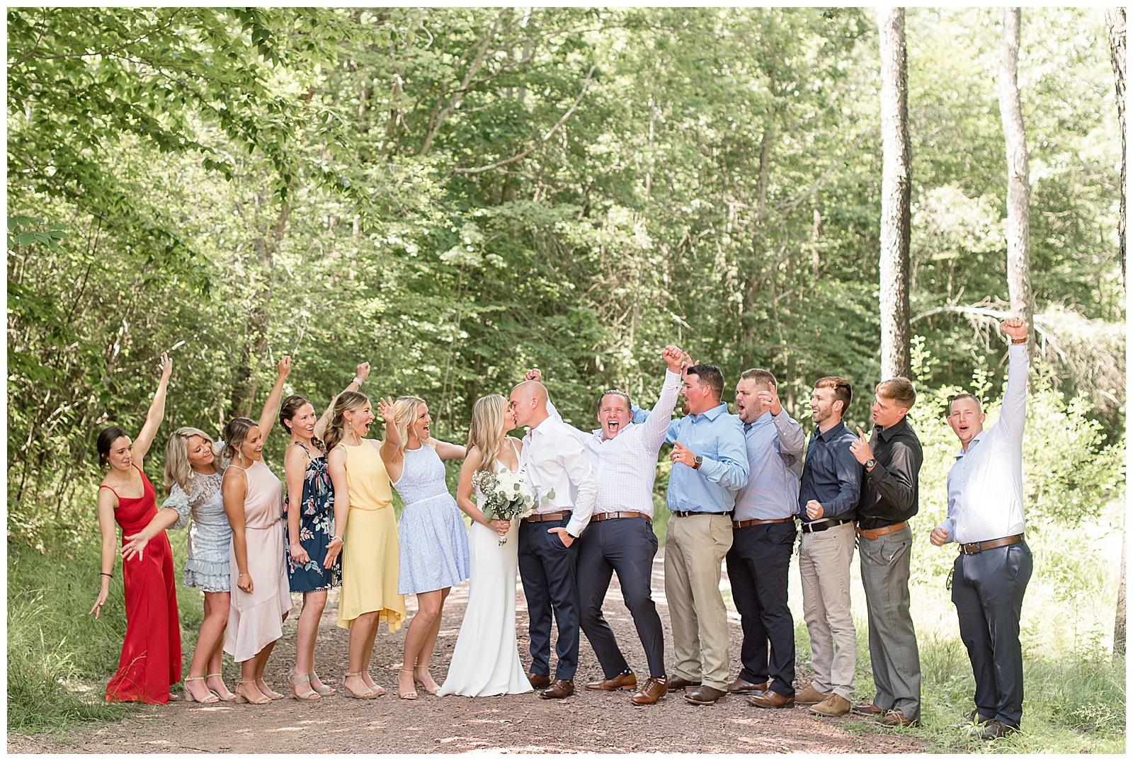 full bridal party cheering as couple shares kiss