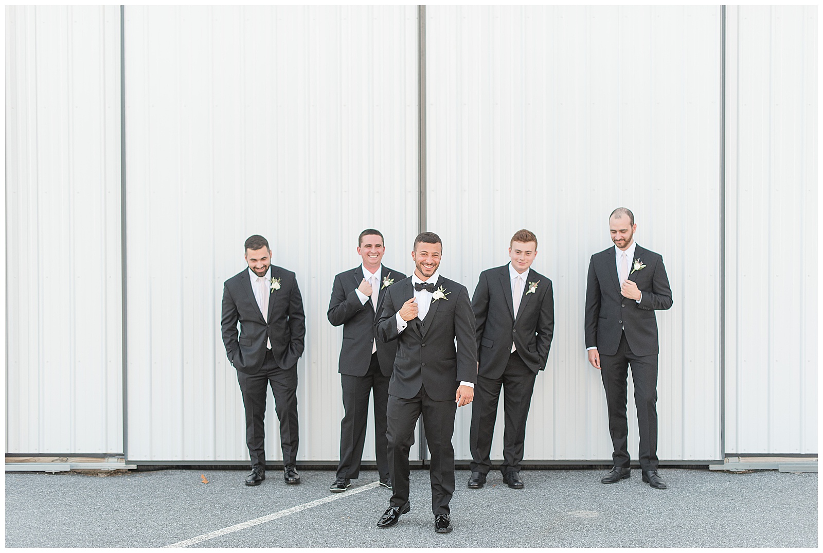groomsmen walking in front of hay barn at the Barn at Silverstone