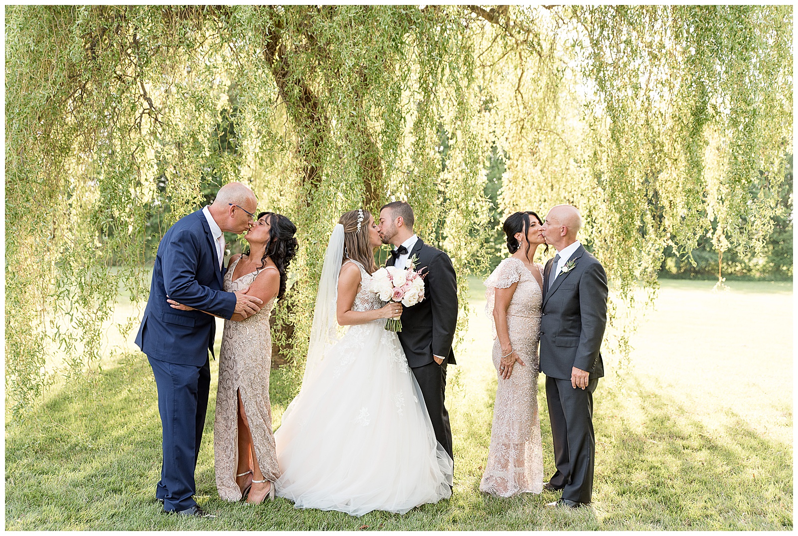 bride and groom with each of their parents with each couple sharing a kiss in front of willow tree