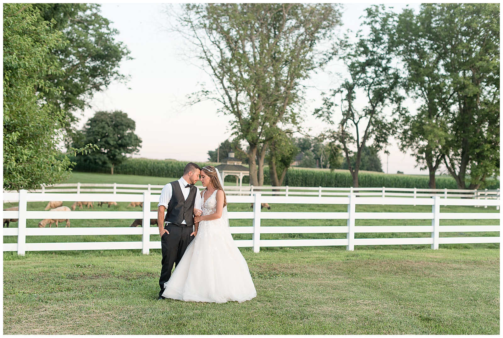 bride and groom resting forehead together during sunset photos in front of white fence