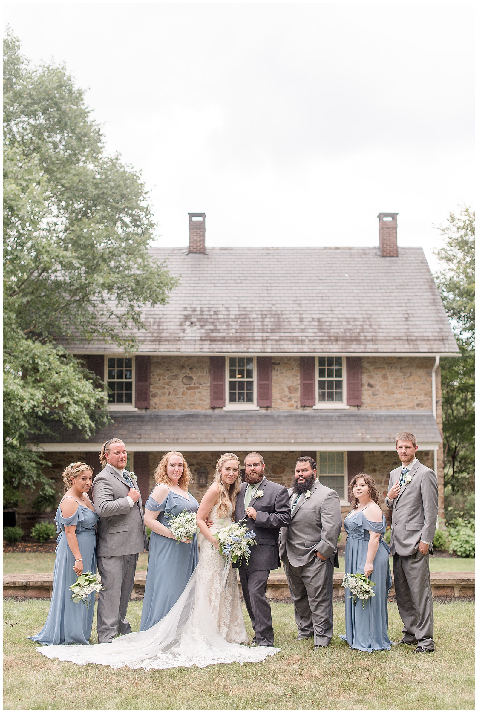 full bridal party in front of farmhouse