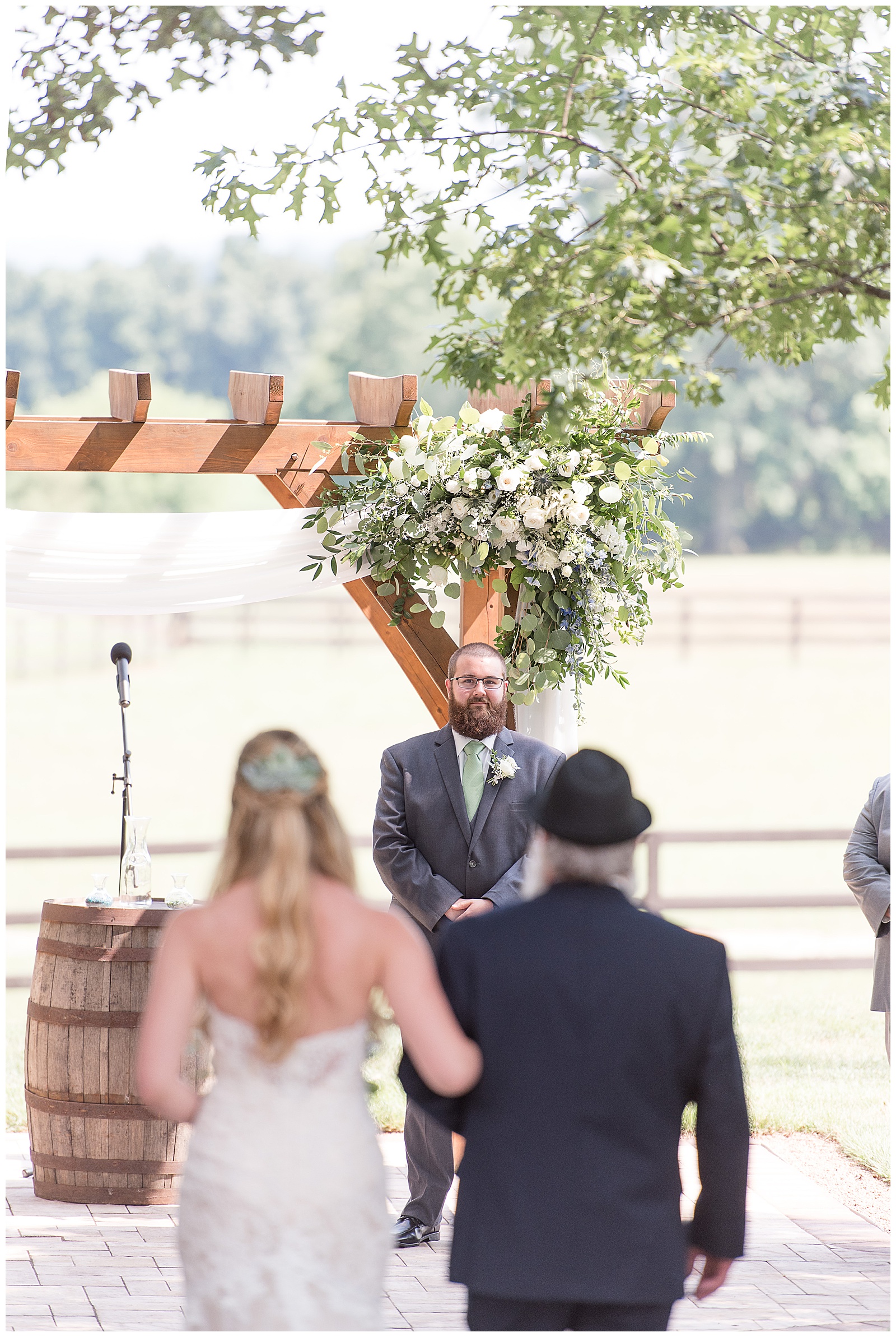 groom smiling as bride comes down aisle with her dad