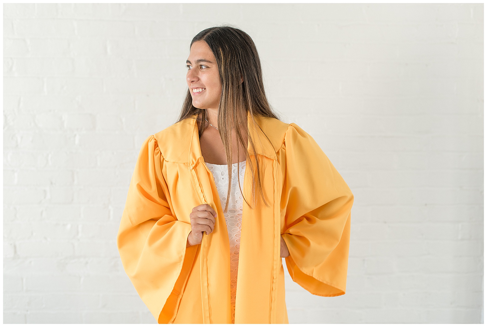 senior smiling off camera in her yellow graduation gown