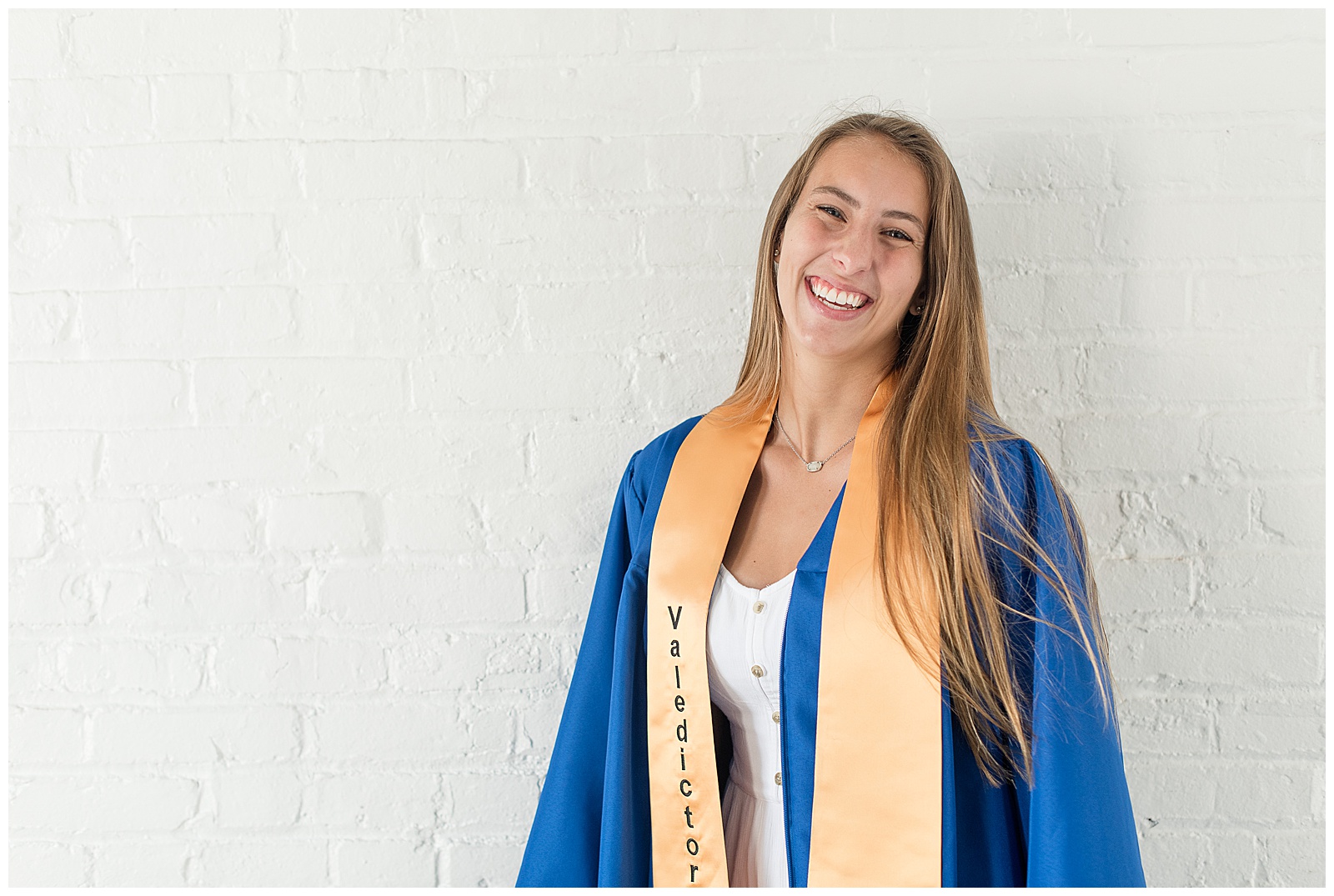 senior laughing at camera with blue graduation gown on