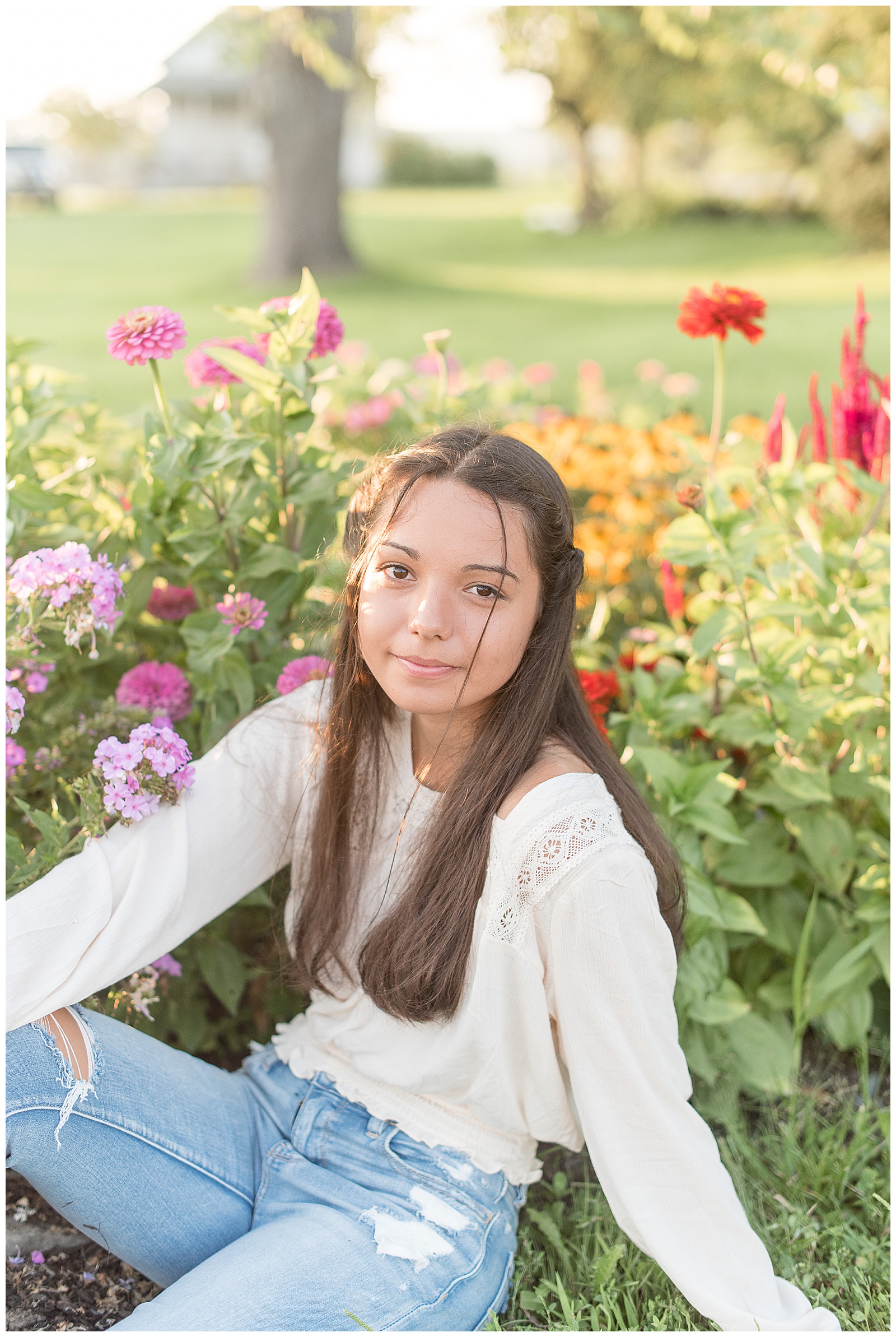 senior sitting with florals around her smiling at camera