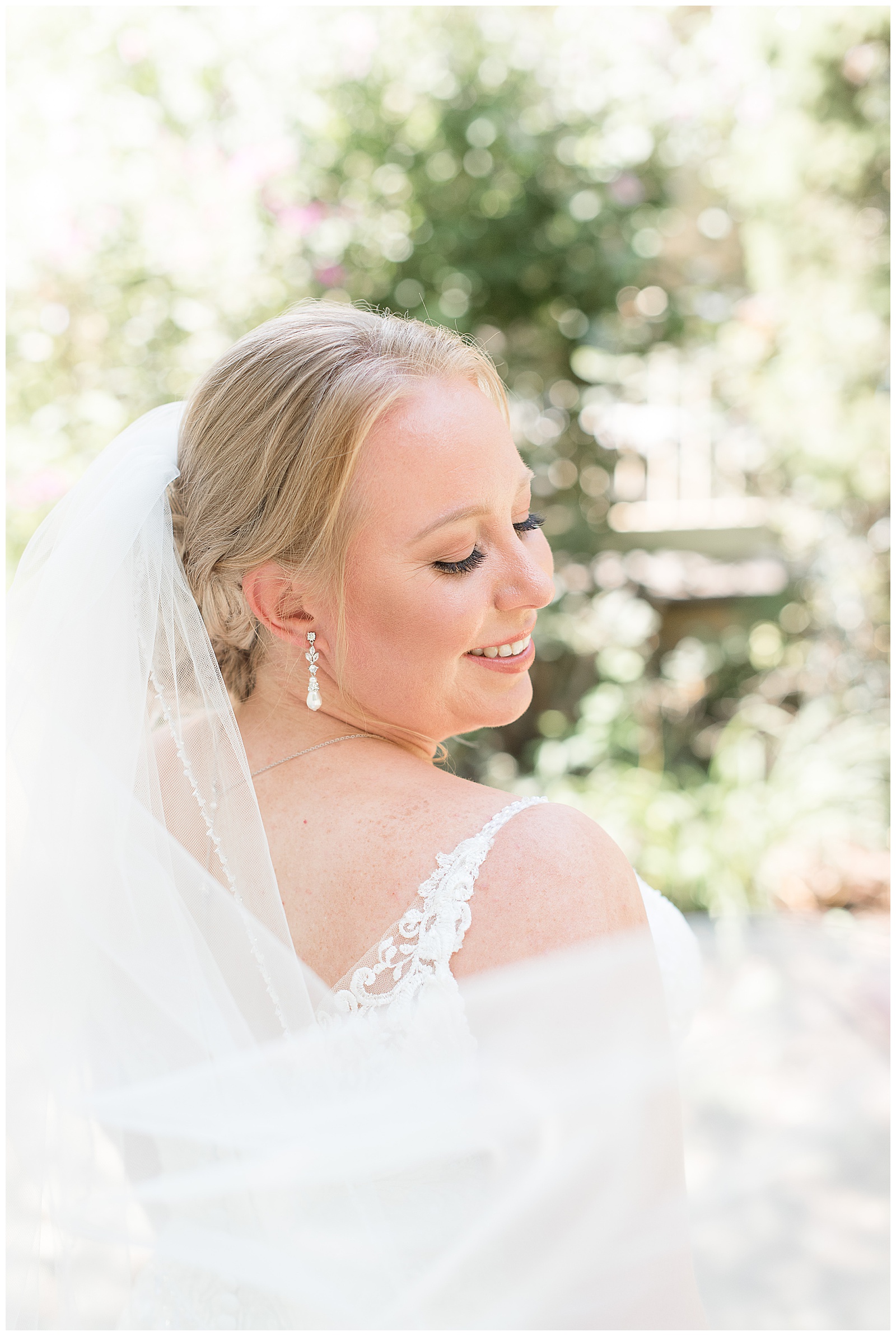 bridal portrait of bride smiling over shoulder with veil flowing in front of her