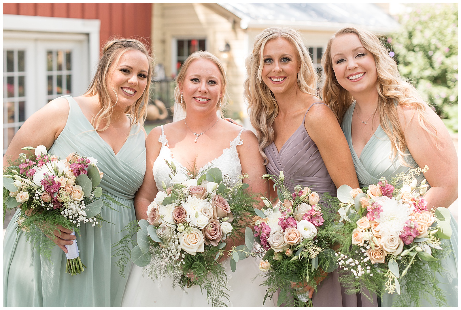 bridesmaids photo with white and pink flowers standing in front of red barn