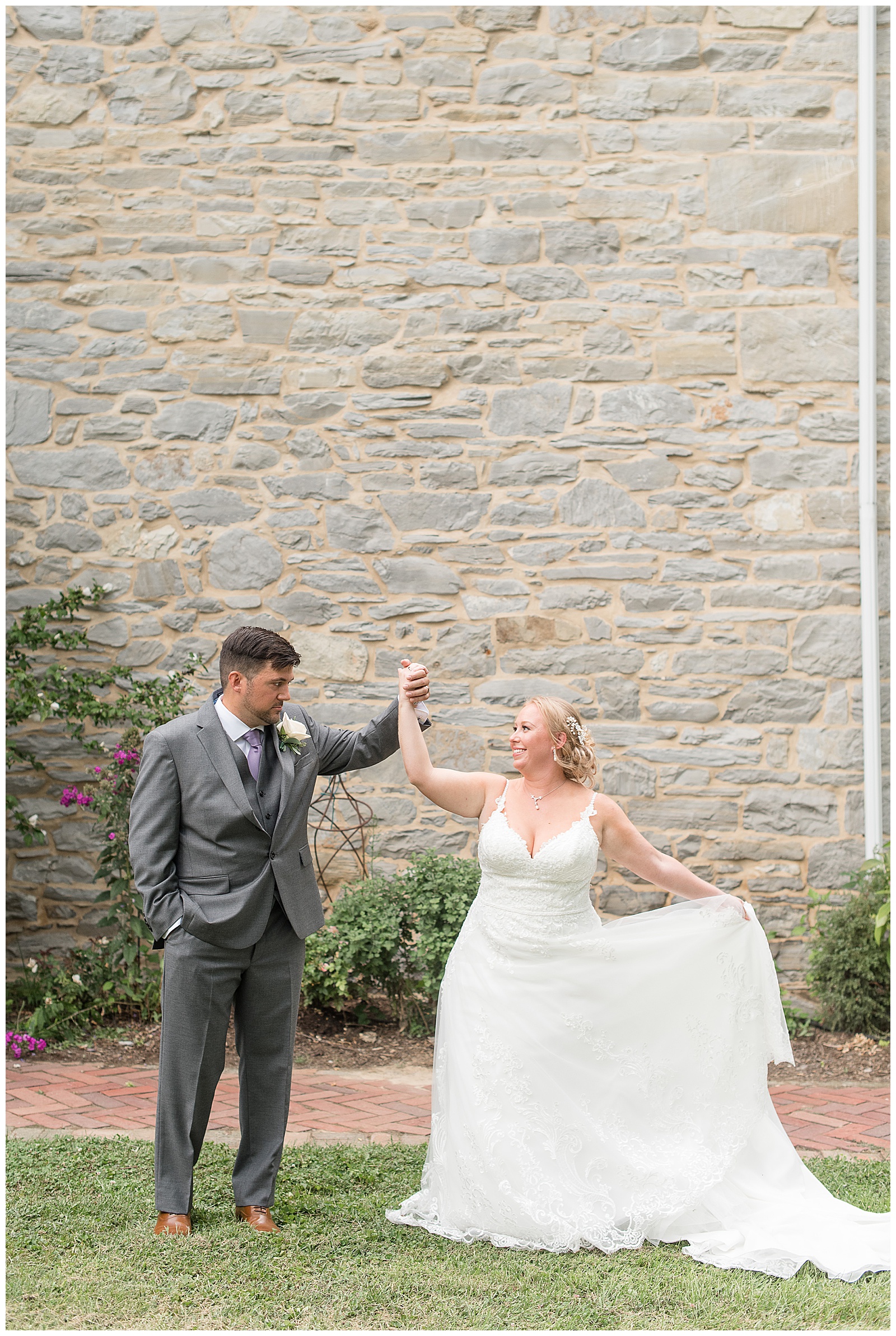 groom twirling bride in front of stone wall at Fallen Tree Farms Bed and Breakfast