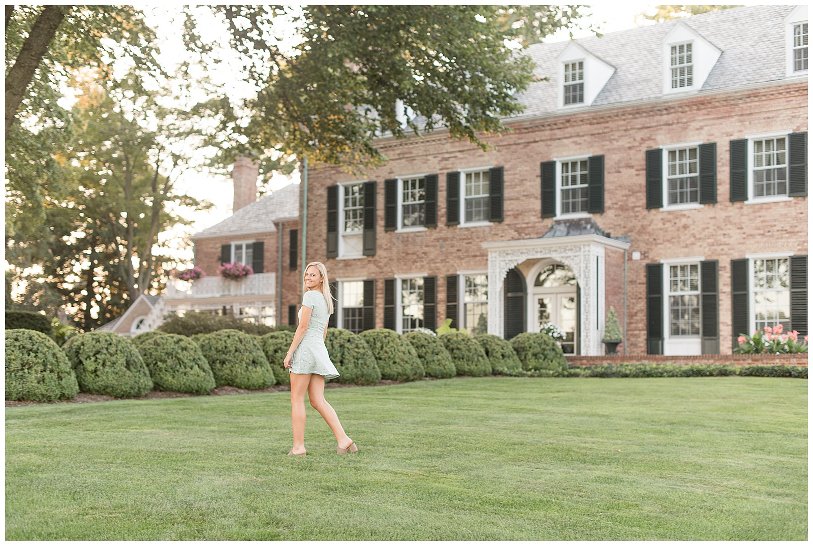 senior walking across lawn in front of Drumore estate smiling over shoulder to camera