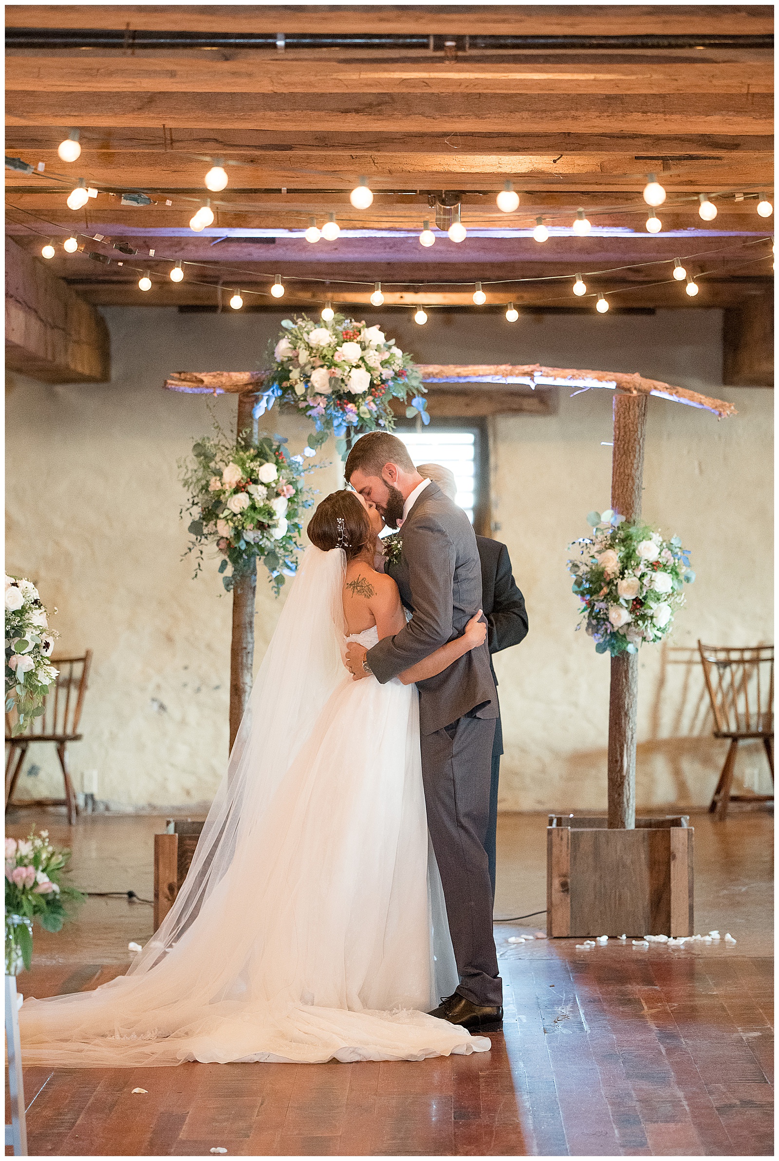 bride and groom share first kiss at ceremony inside barn at Country Barn