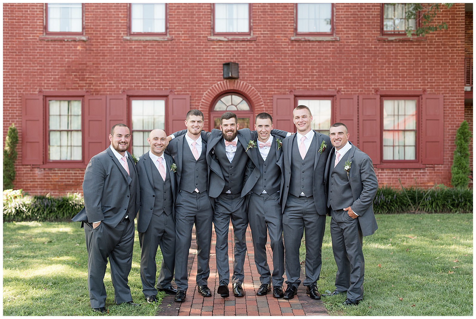 groom and groomsmen wrapping arms around each other smiling at camera
