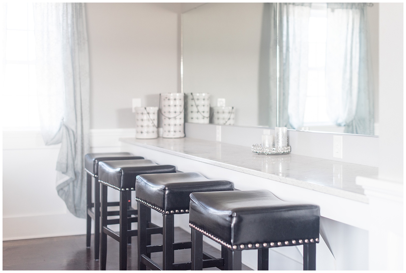 close up photo of row of black leather stools lined up along white countertop and mirror in bridal suite at The Barn at Stoneybrooke in Atglen, PA