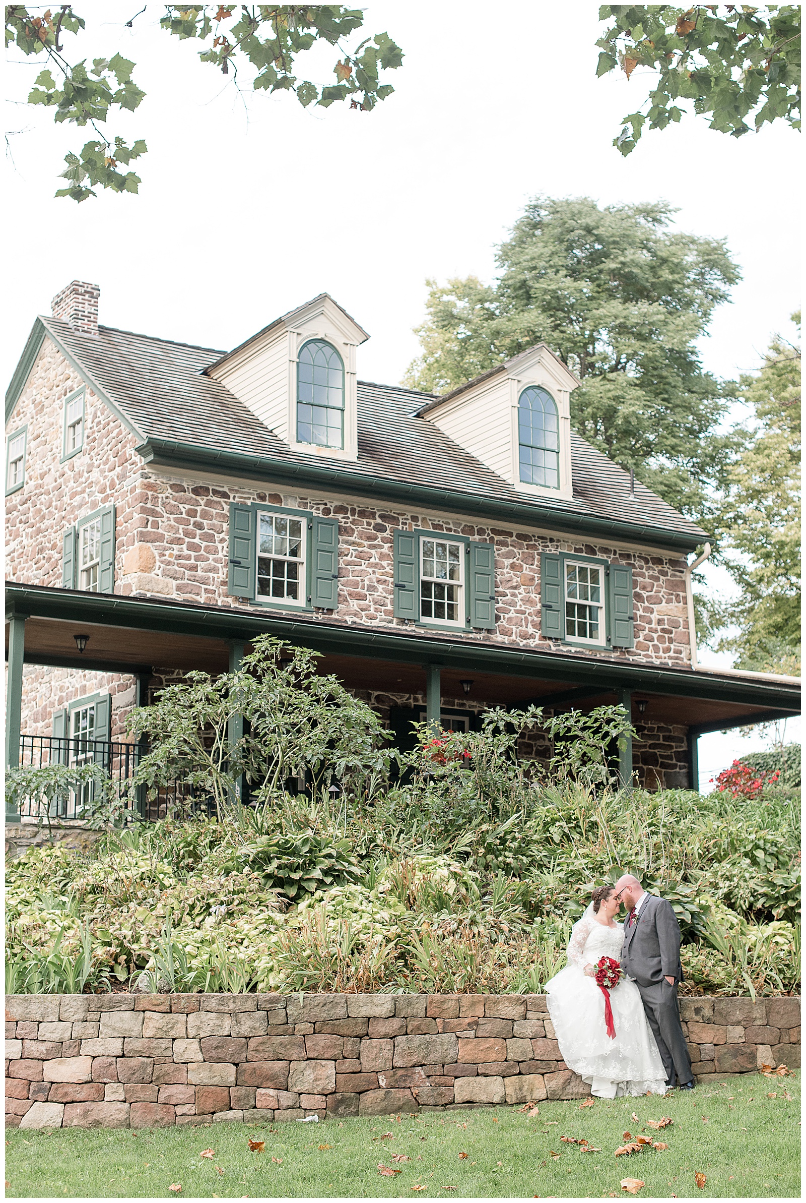 couple standing in front of beautiful stone home at historic poole forge in lancaster pennsylvania