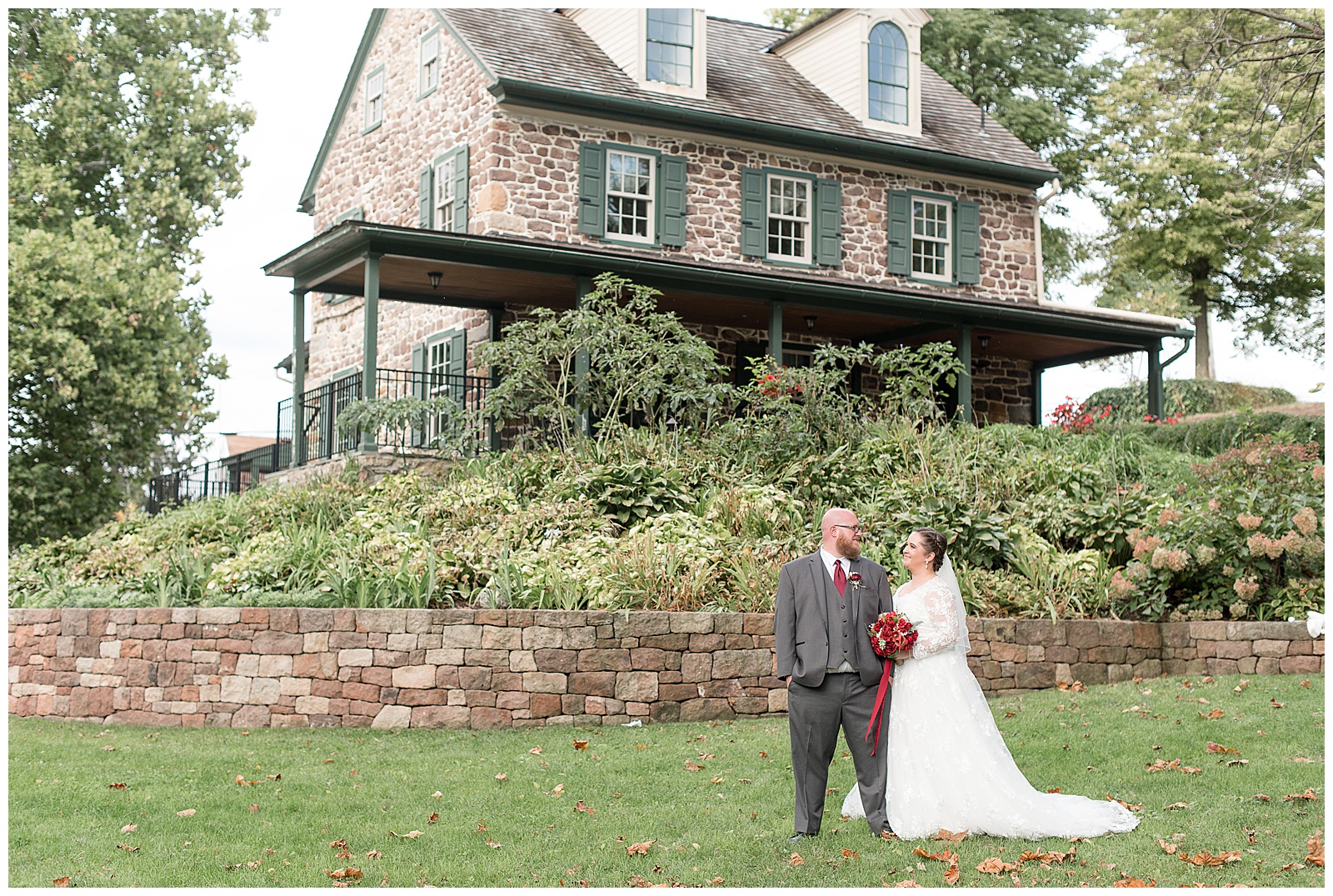 groom and bride smiling in front of stone home at historic poole forge in lancaster pennsylvania