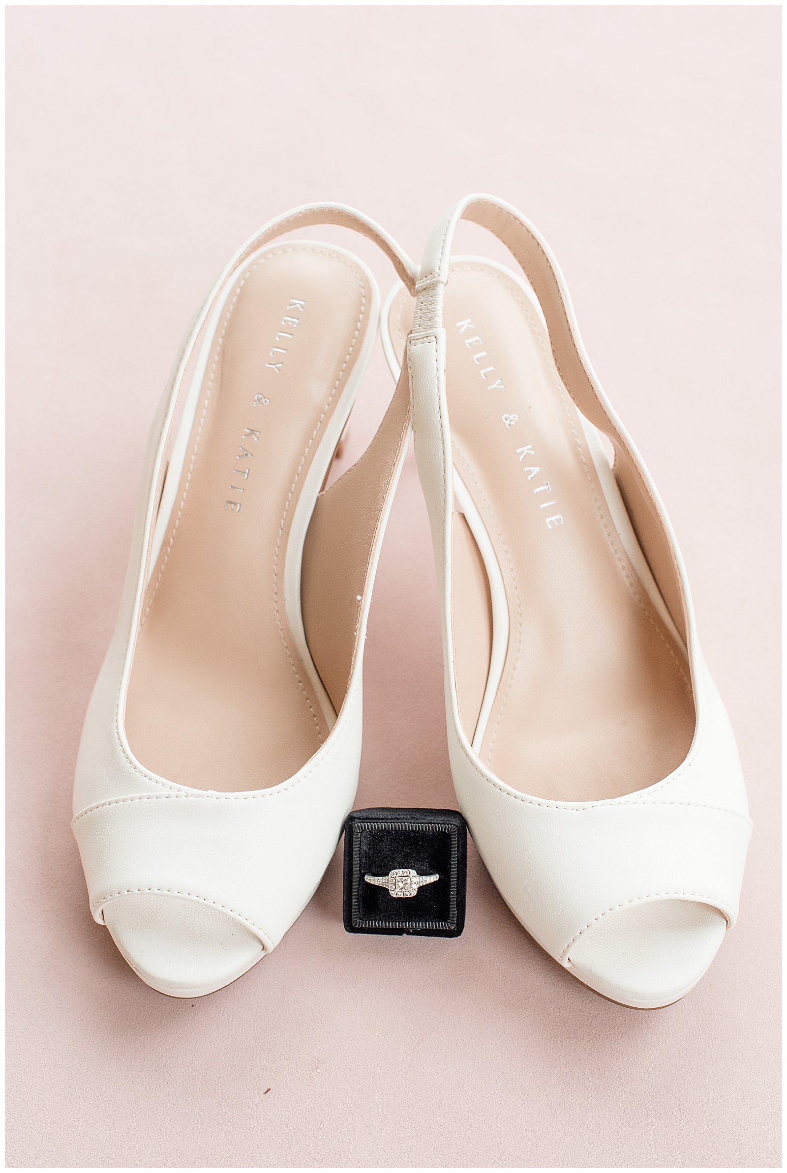 brides white shoes with diamond ring in black box on blush background