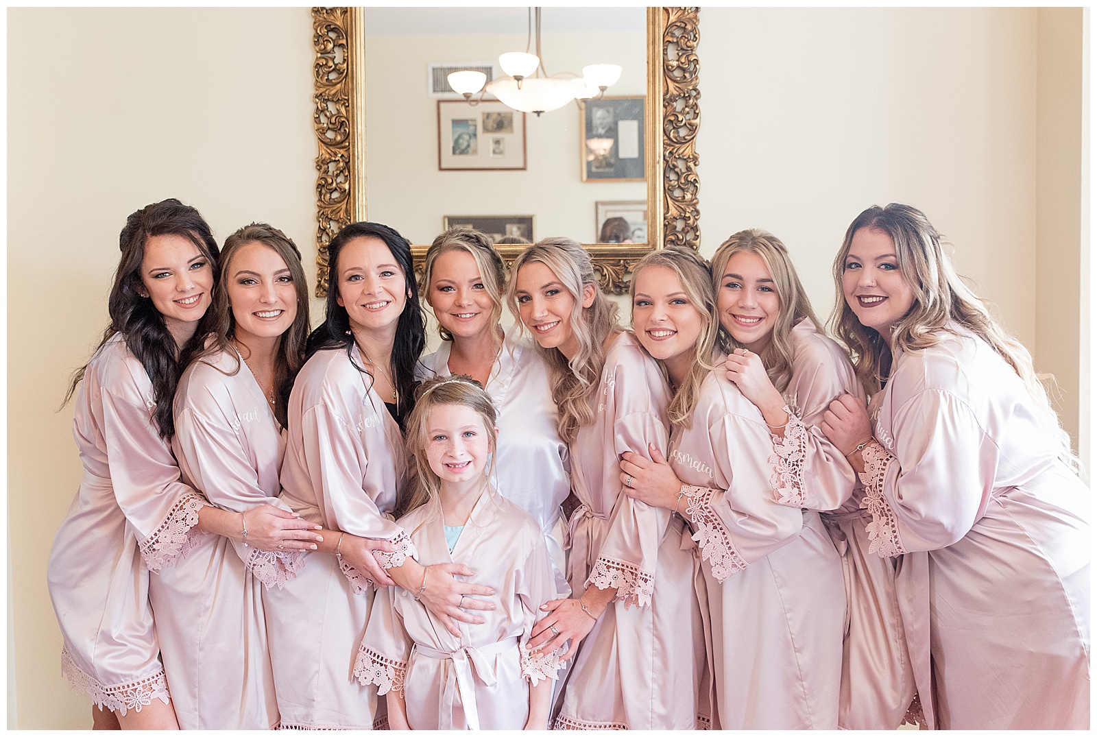 bride and bridesmaids in blush robes standing close and hugging at hayfields country club
