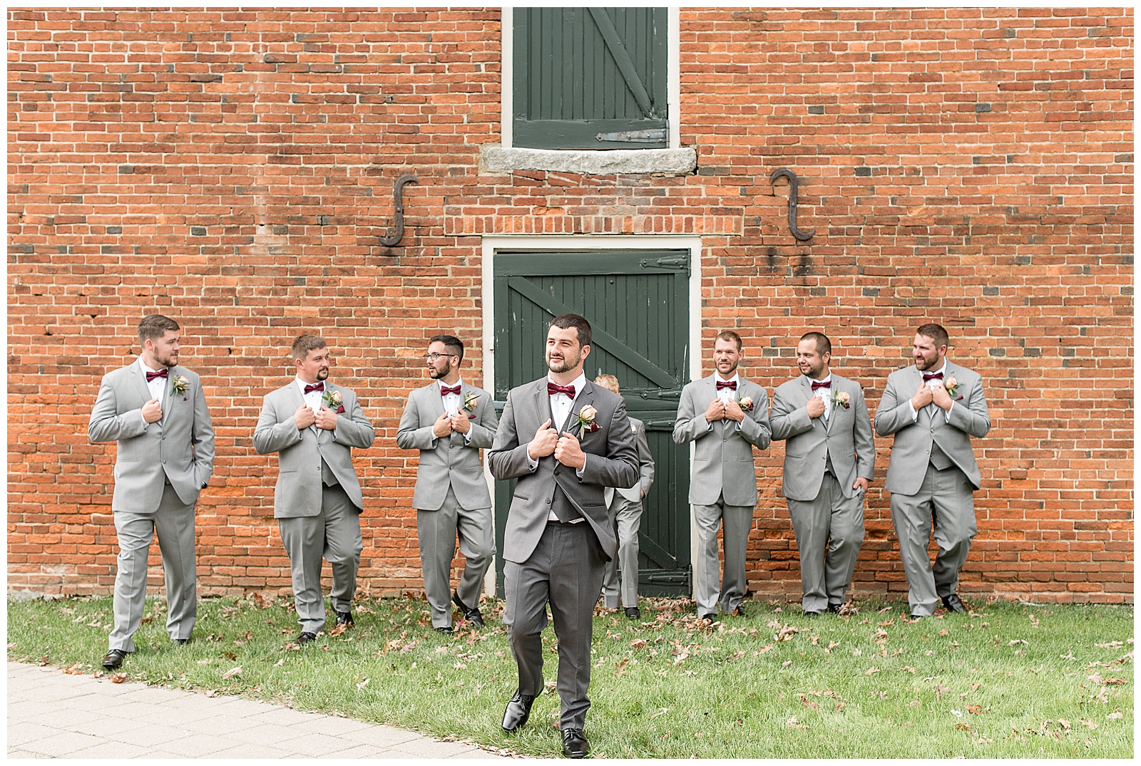 groom with groomsmen adjusting their ties walking in front of brick building at hayfields country club