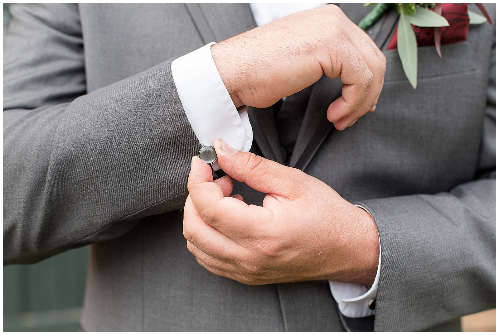 groom holds cuff link of gray suit at hayfields country club